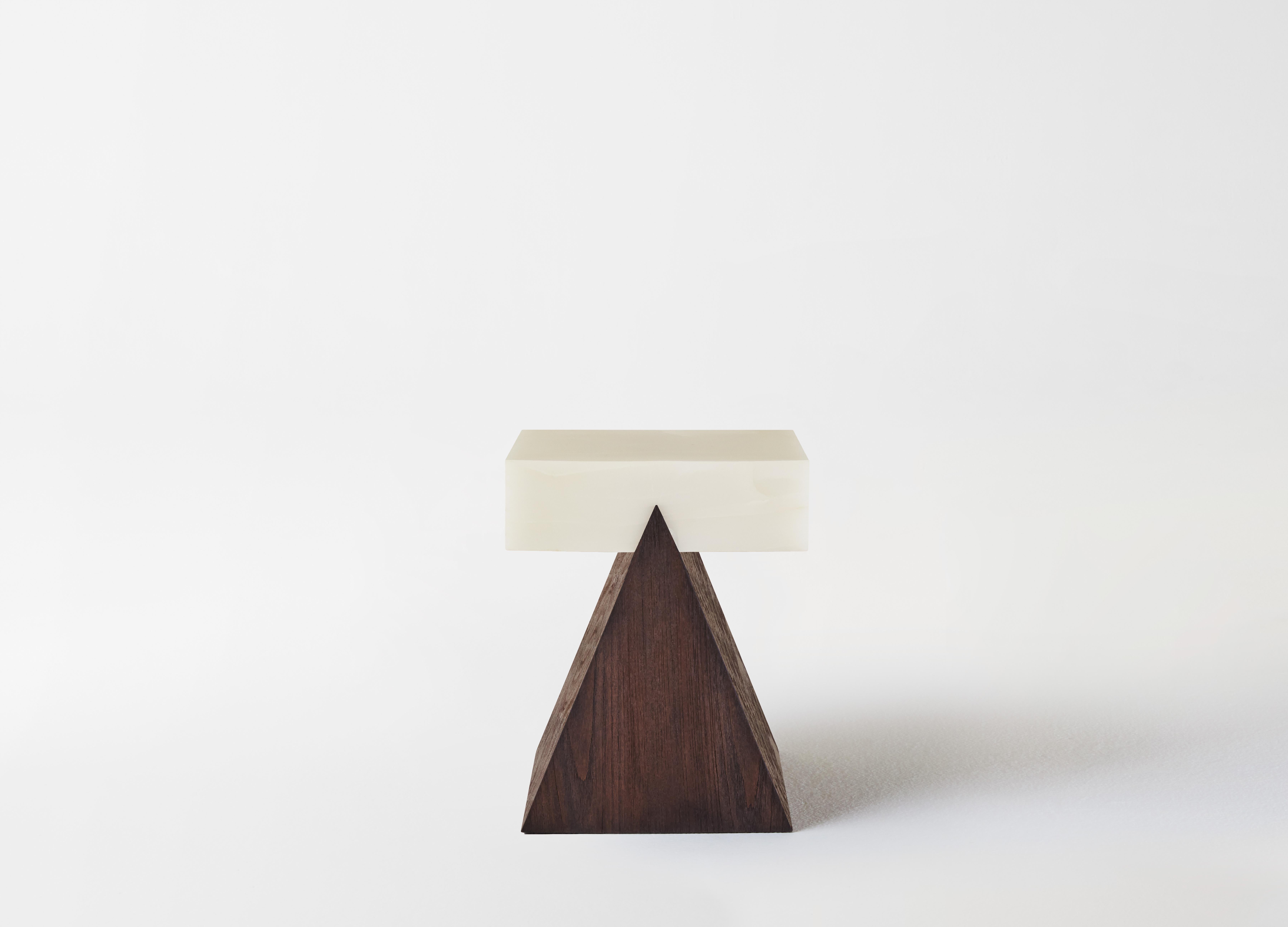 Aman’s Trini Side Table combines craftsmanship with spiritual resonance. The triangular shape stands as testament to strength, stability, and unity. The juxtaposition in the materiality – with its wooden base and immense Onyx top – invite an