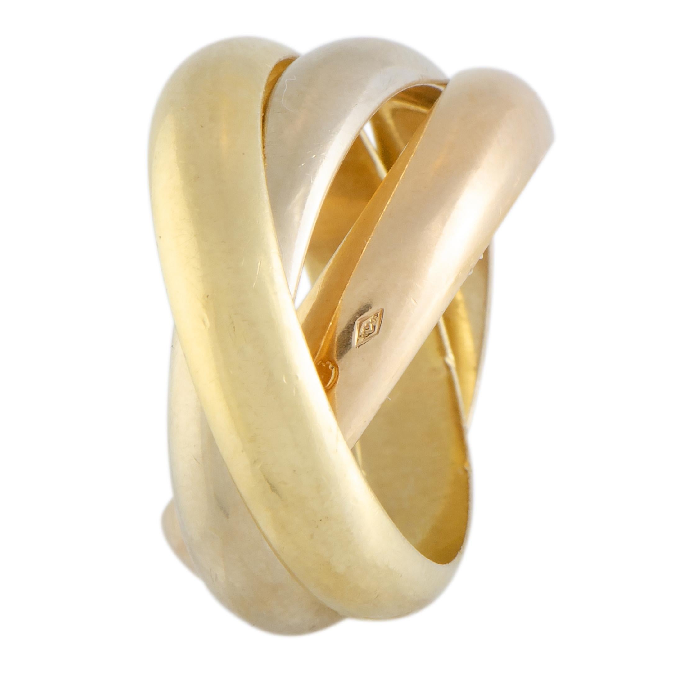 This fascinating trinity ring by Cartier is an item of prestigious quality and refined aesthetic style. The elegant ring is beautifully designed by interloping three bands that are made from a spectacular combination of shimmering 18K yellow, white