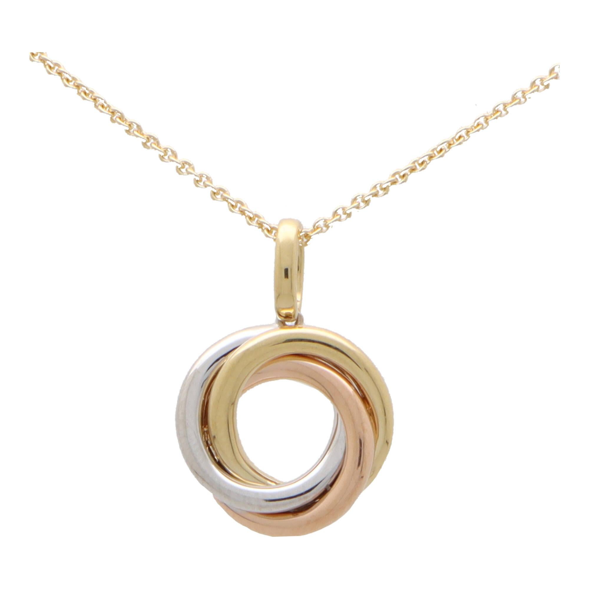  A classic trinity ring pendant necklace set in 18k yellow, rose and white gold. 

This iconic pendant design is composed of three tri-coloured loops interlocked into one pendant. It hangs from a yellow gold bail on a 16-18-inch yellow gold trace
