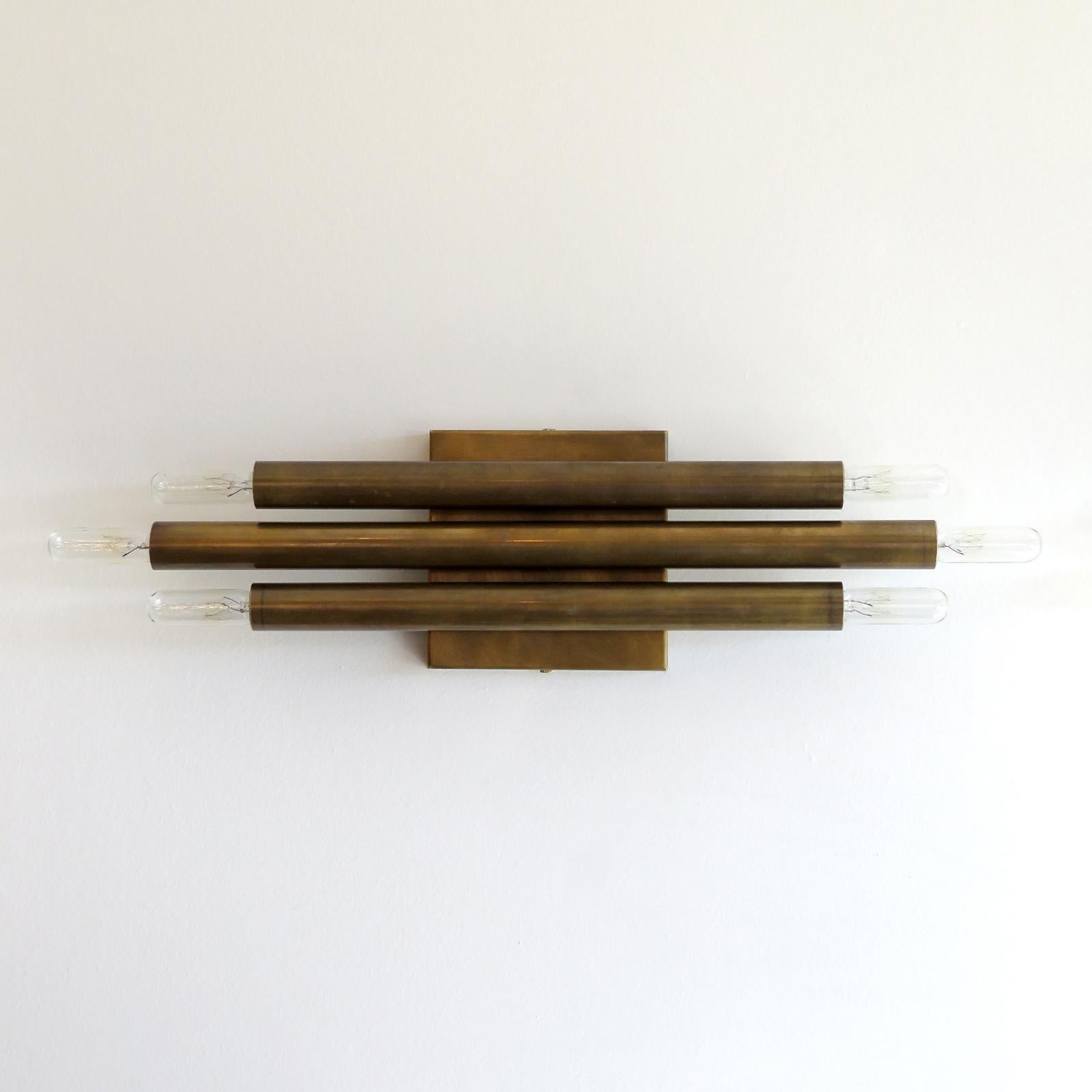 Estupendo par de apliques geométricos de latón envejecido de Gallery L7, fabricados y acabados a mano en Los Ángeles, con tres velas dobles de latón que pueden montarse vertical u horizontalmente. Seis enchufes candelabro E12 por aparato, potencia