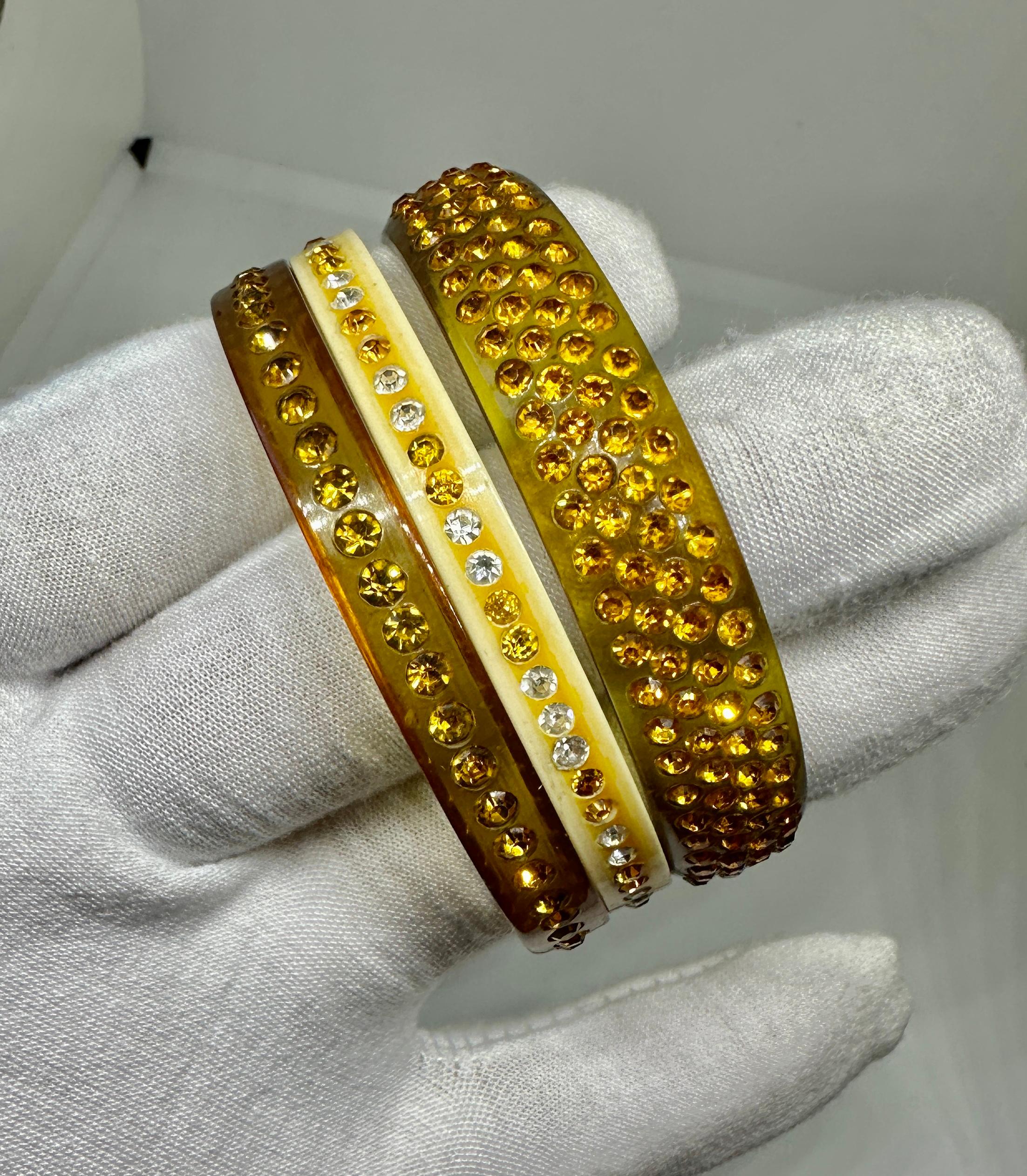 VOICI UN MAGNIFIQUE TRIO DE 2 BRACELETS ART DÉCO EN CELLULOÏD ET STRASS DE COULEUR AMBRE ET 1 BRACELET DE COULEUR CRÈME.
LES BRACELETS ONT UN FABULEUX STYLE DÉCO RÉTRO AVEC DES STRASS ET DU CELLULOÏD.  LES BRACELETS SONT DES BIJOUX CLASSIQUES DE