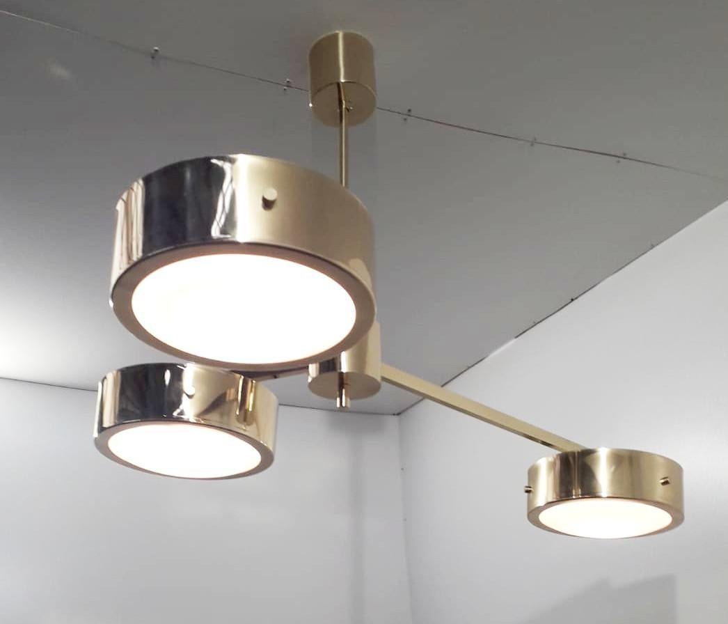 Pendente moderno italiano con tre paralumi in vetro di Murano bianco lucido racchiusi in eleganti bande di ottone lucido e montati su una struttura in ottone lucido. 
Disegnato da Fabio Bergomi / Made in Italy
3 luci / tipo E12 o E14 / max 40W