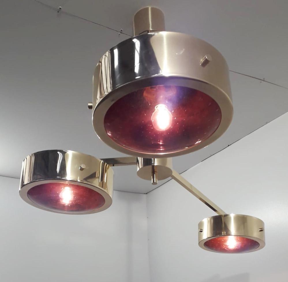 Suspension moderne italienne avec trois abat-jour en verre de Murano améthyste soigneusement soufflés à la main avec des bulles à l'intérieur du verre en utilisant la technique Bollicine, entourés de bandes de bordure chic en laiton poli et montés