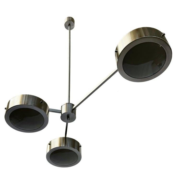 Suspension moderne italienne avec trois abat-jours en verre de Murano gris brillant entourés de bandes chic en nickel satiné et montés sur une monture en nickel satiné. 
Design/One / Fabio Bergomi / Made in Italy
3 lampes / type E12 ou E14 / max 40W