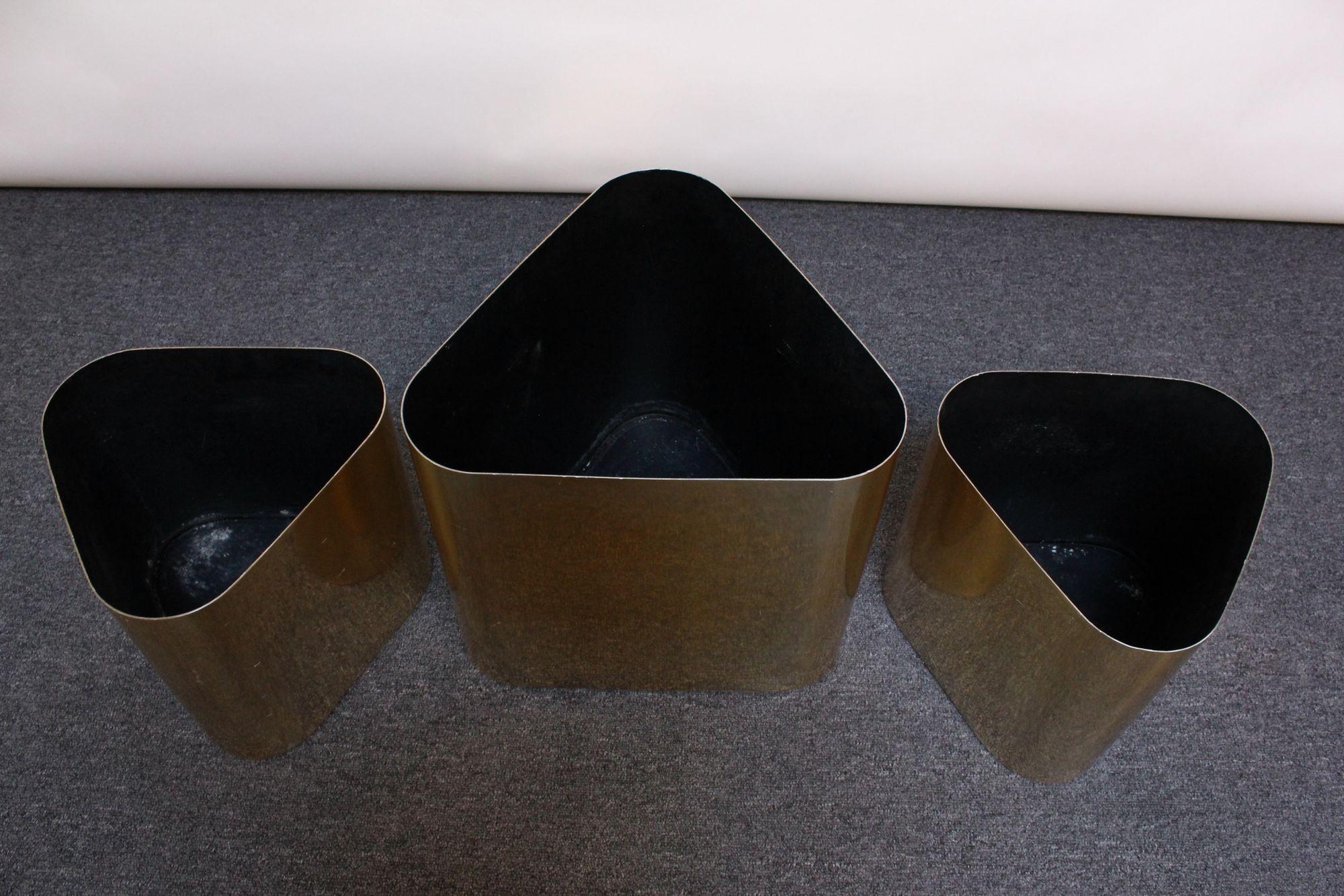 Set of three large planters designed in the 1970s by Paul Mayen for Habitat International.
Uncommon triangular form in aluminum with a brassy/gold finish.
Reflective exterior shows scratches and black interior shows general wear/soiling from use.