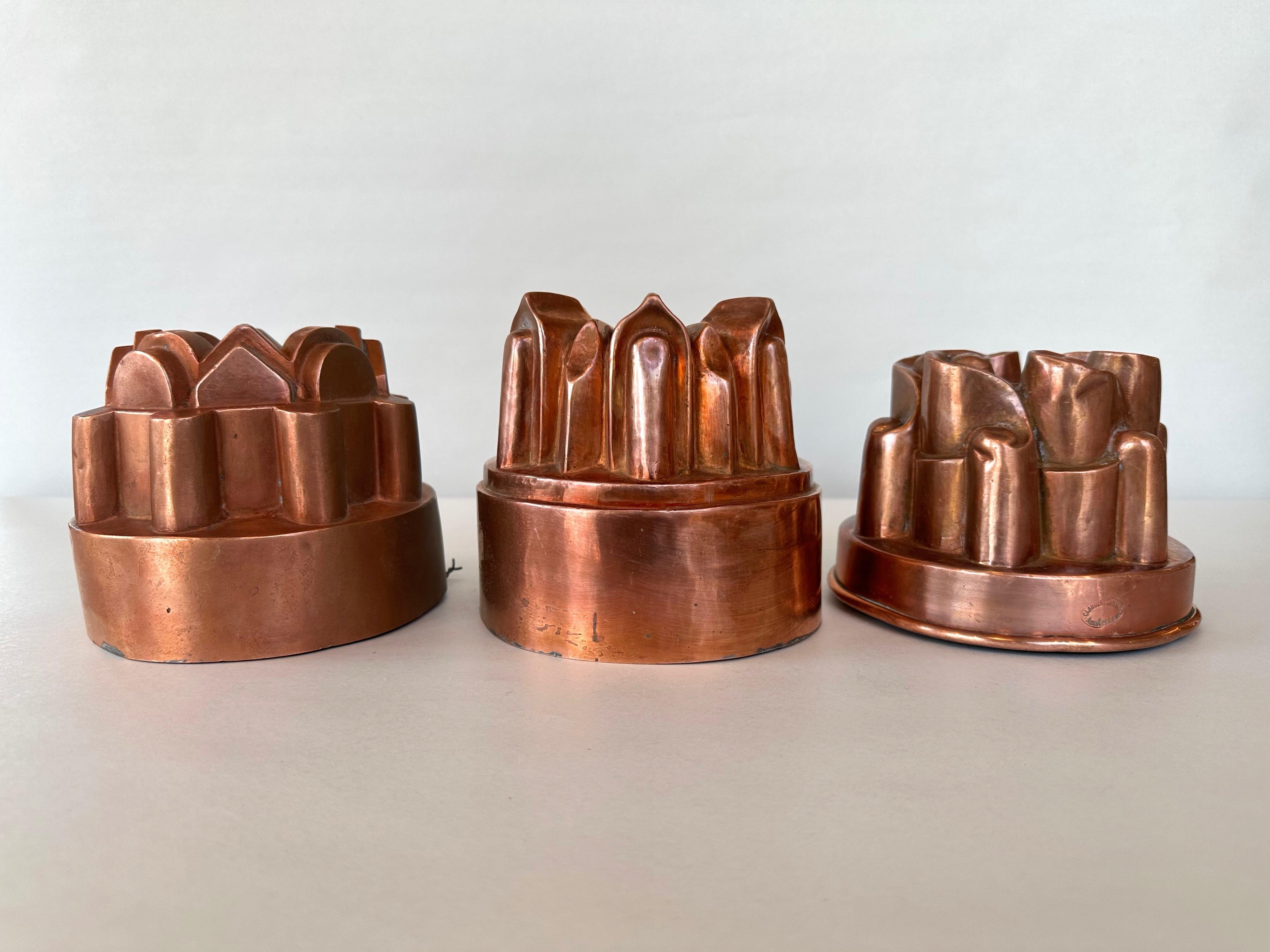 A charming set of three circa 1910 architectural and whimsical copper cake, jelly, or pudding baking molds from France and the Netherlands, with two bearing maker’s marks.

Described as pictured from left to right:

Mold at left with a crisply-done