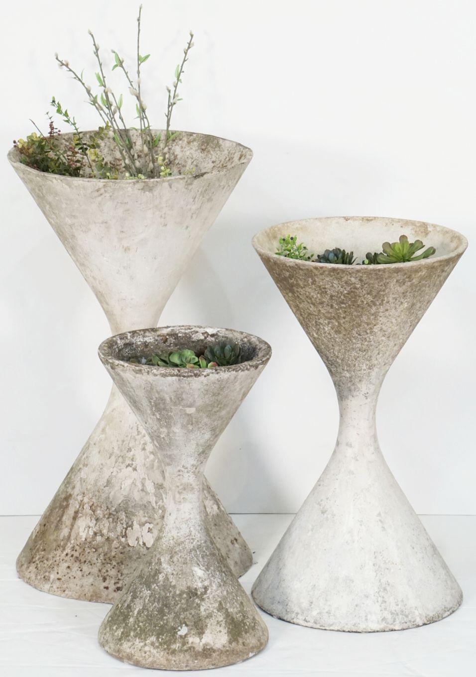 A fine trio of Mid-Century Modern hour-glass shaped spindel planter pots or urns of composition cement - in varying heights - for an indoor or outdoor garden, garden room, or terrace - designed by the iconic Swiss designer, Willy Guhl. 

Swiss