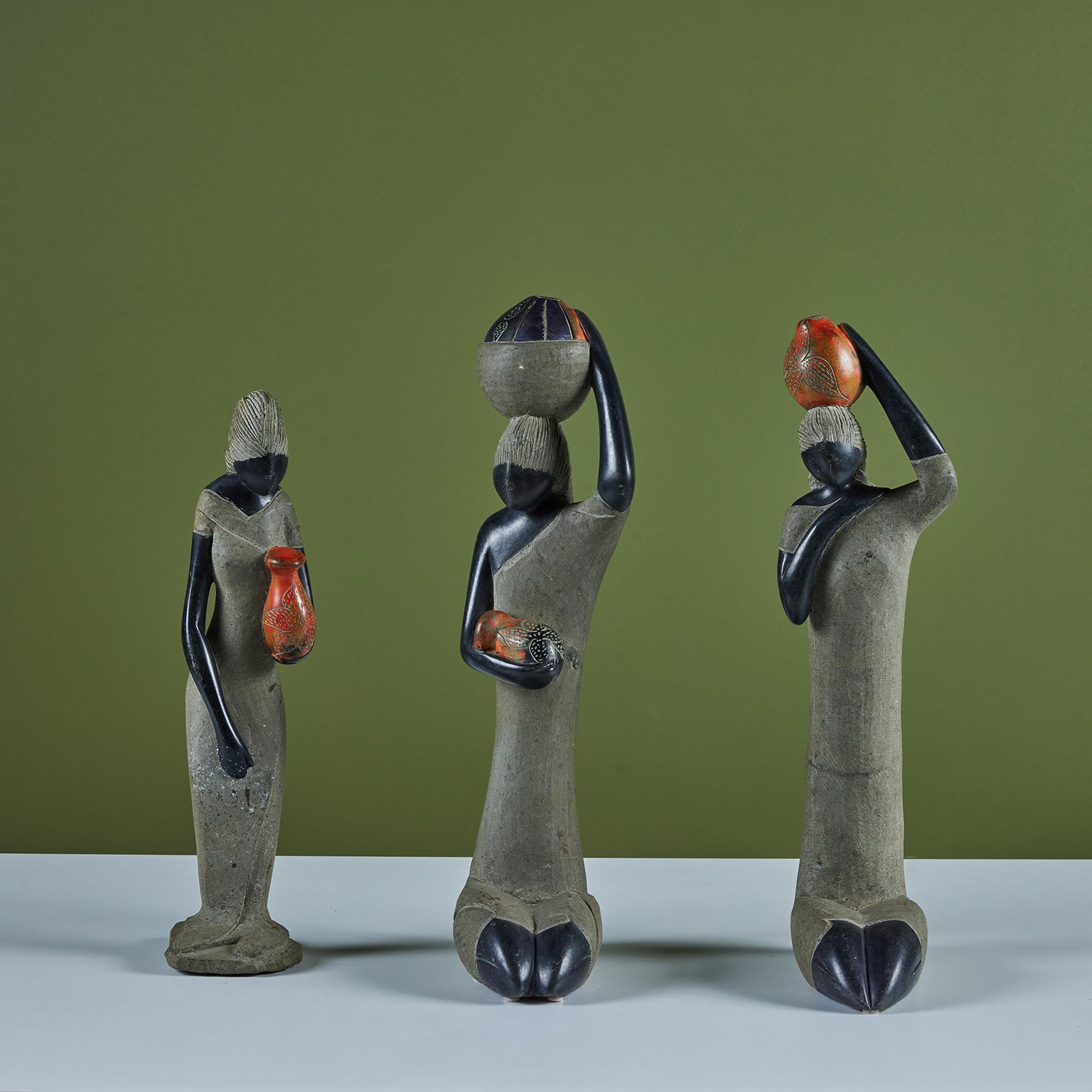Set di tre donne scolpite in pietra che portano ciascuna un recipiente d'acqua tra le braccia. Questa forma d'arte proveniente dallo Zimbabwe è diventata una decorazione popolare alla fine degli anni '50, ma è stata prodotta per decenni prima di