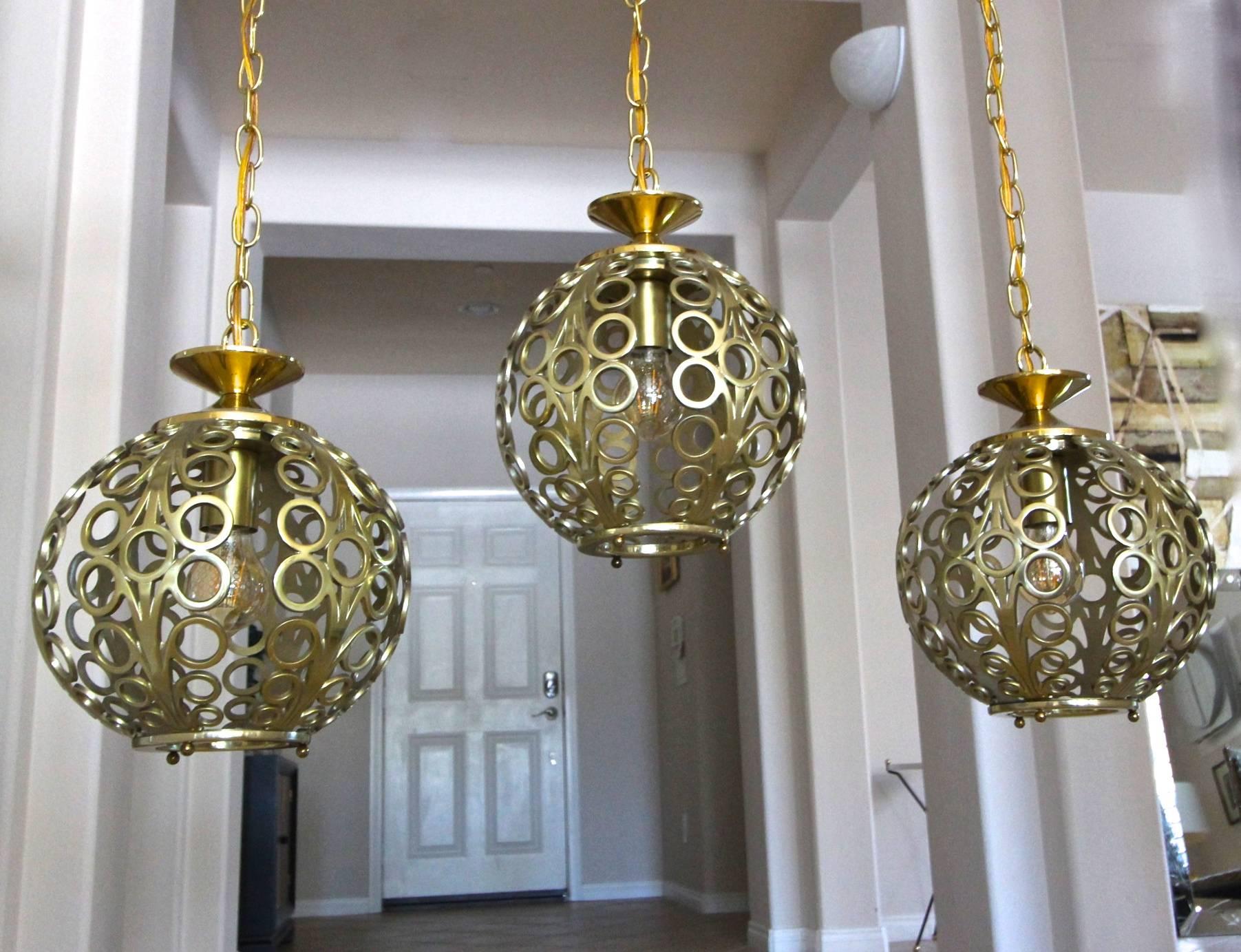 Trio of vintage pendants with circle motif in brass finish, each hangs separately. New light sockets, chain and ceiling caps. Overall length each pendant 53