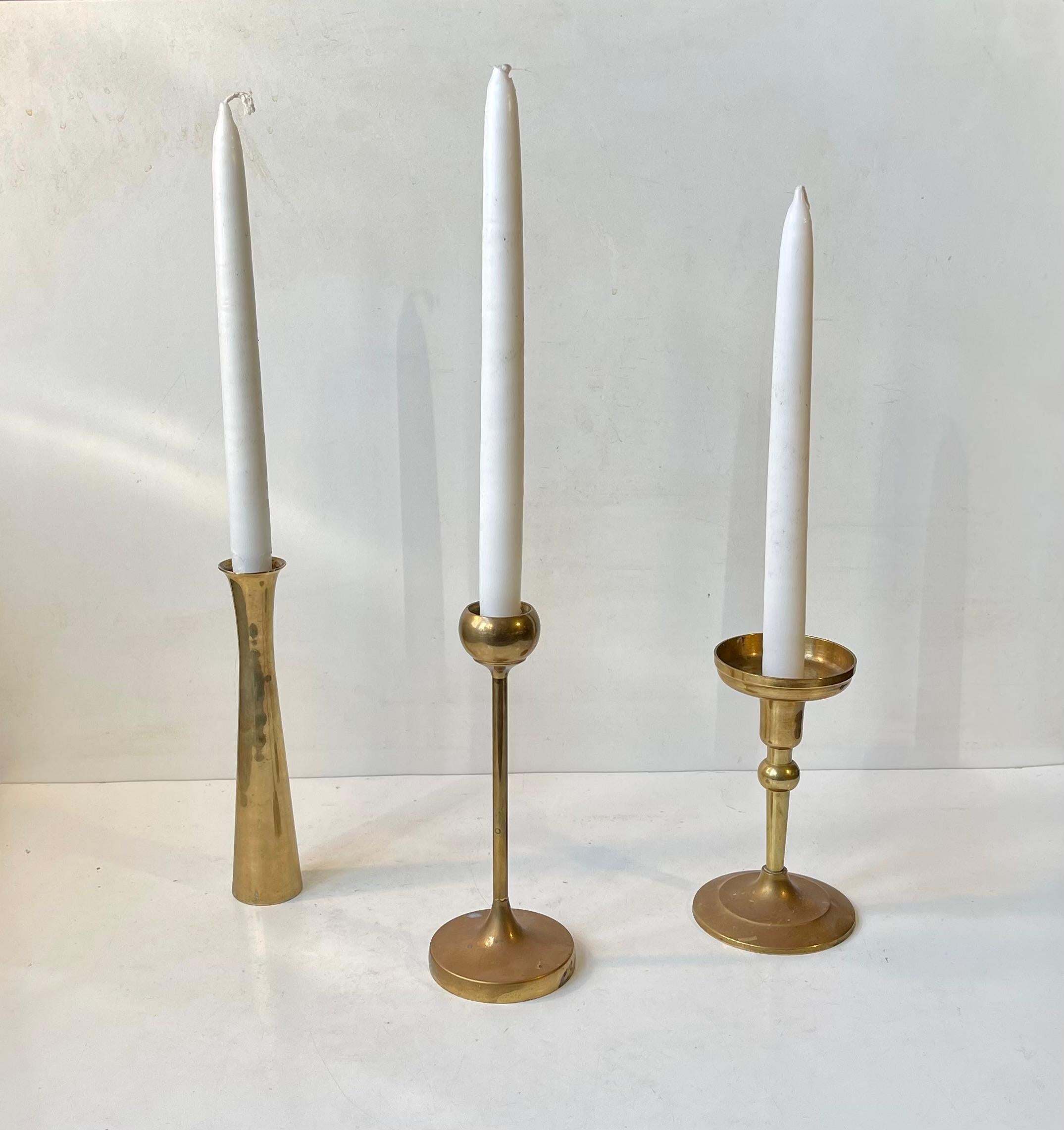 A trio of solid brass candlesticks manufactured in Denmark during the 1970s. The candlesticks are to be fitted with regular sixed candles. They have not been polished recently and display patina. The style of this set is reminiscent of Quistgaard,