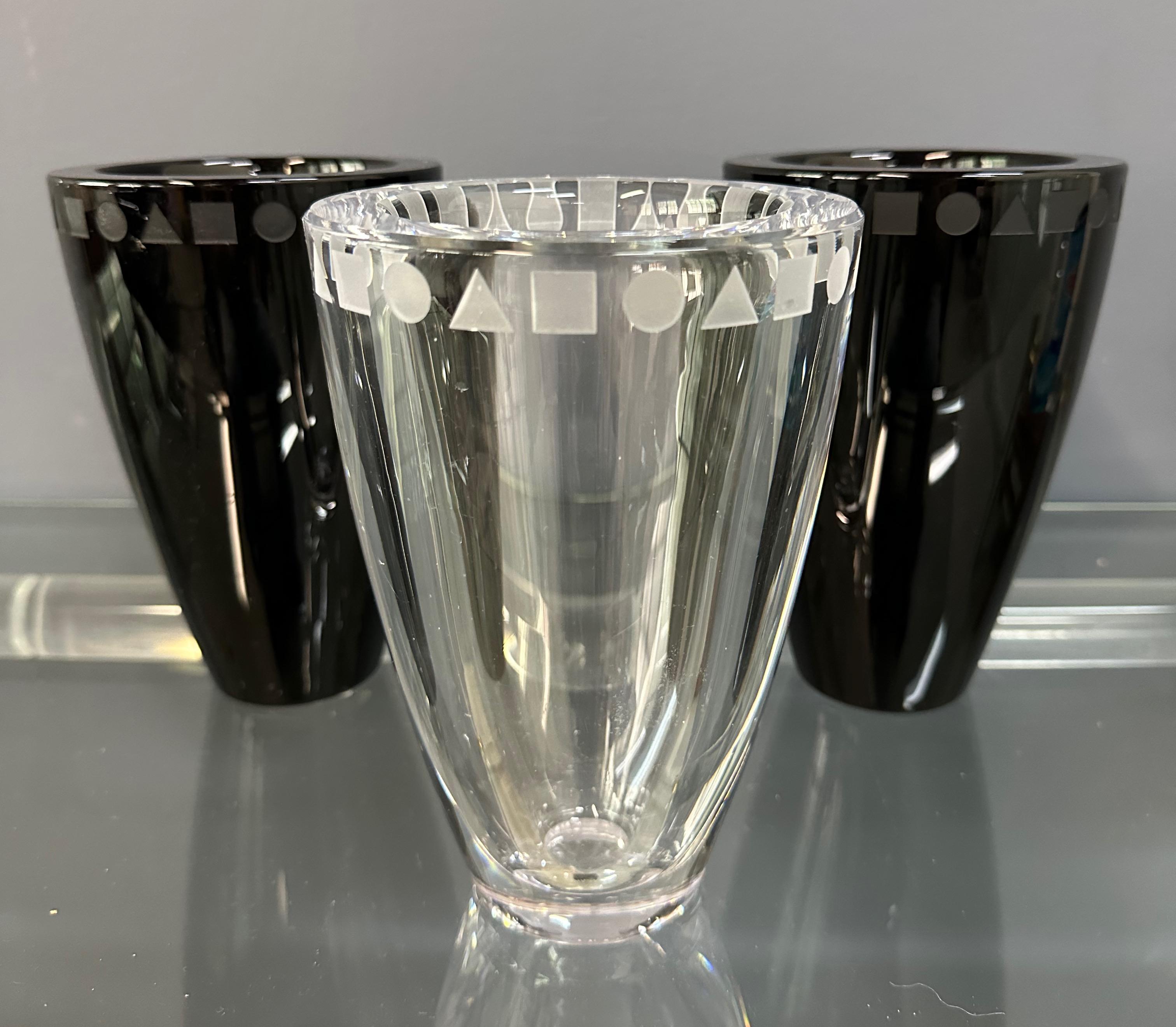 A striking set of three etched crystal vases designed by Ward Bennett for Sasaki, Japan. The grouping features two in deep onyx black and one in clear crystal, each adorned with Bennett’s signature geometric motif of circles, squares, and triangles