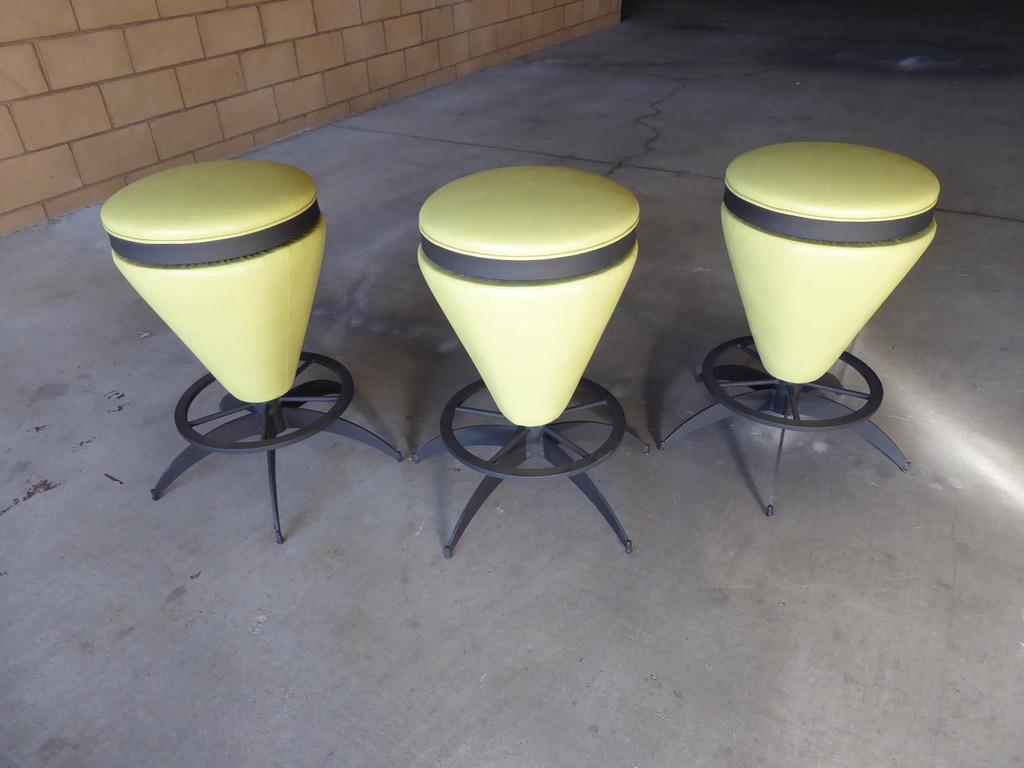 A trio of whimsical and sophisticated 1950s painted iron framed swiveling counter stools in the form of bongo drums. The set has been newly reupholstered in a vibrant green vinyl.