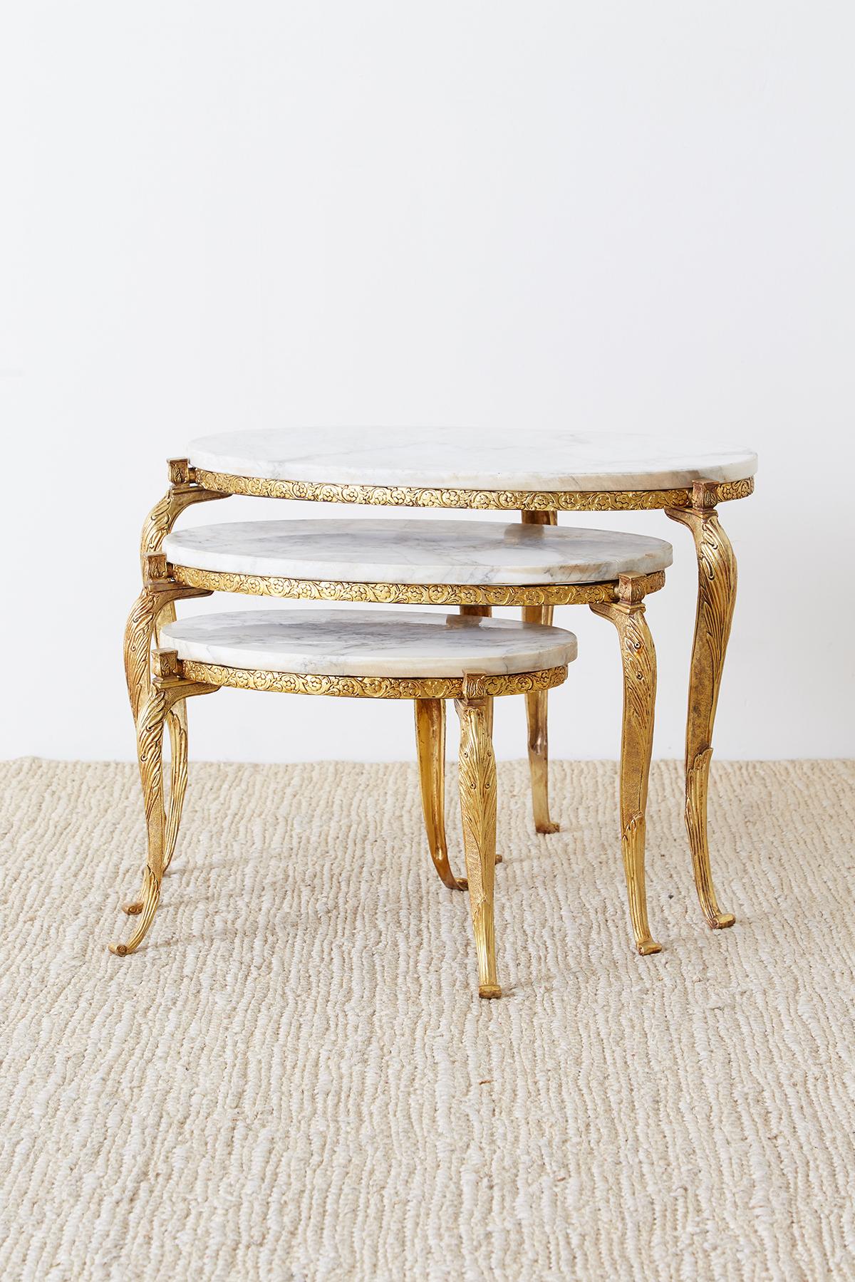 Extraordinary nest of three Italian drinks tables featuring oval Carrara marble tops. Supported by elegant Baroque style cabriole legs made of doré bronze. The three legs are attached to an iron ring with a decorative gilded bronze trim. Produced in
