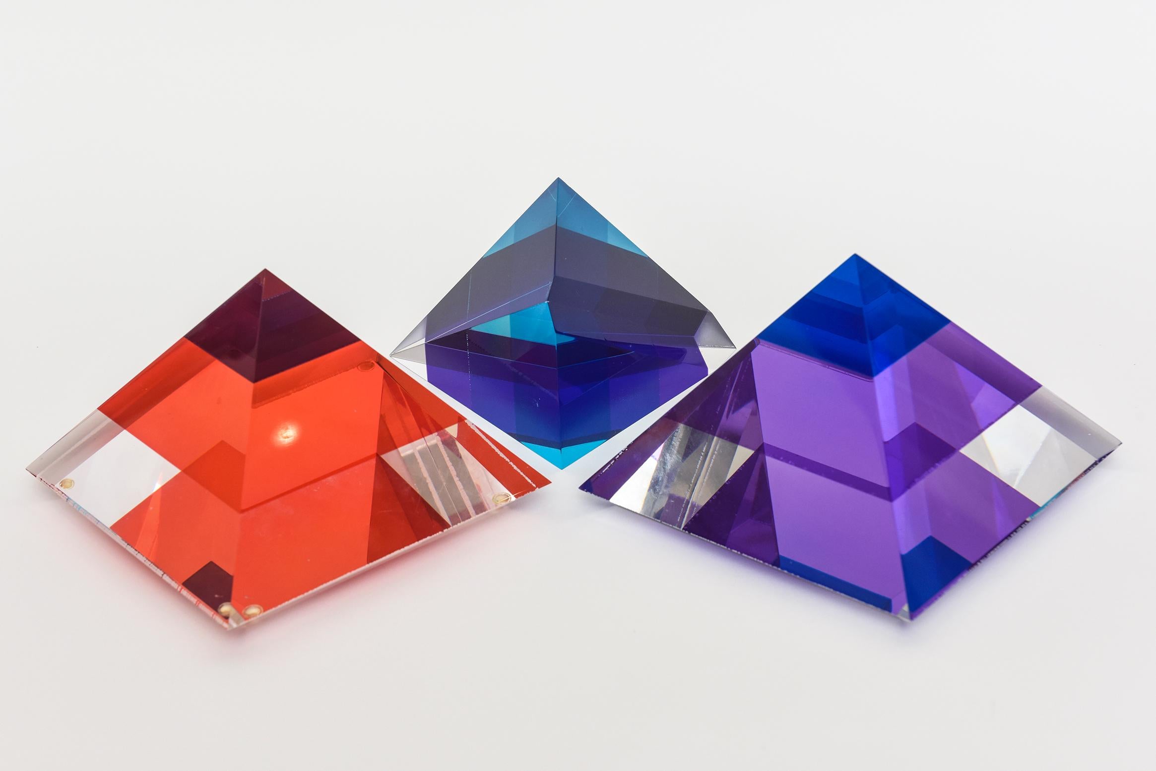 This collection of lucite jewel toned sculptures in orange, red, sapphire blue and purple are two pyramids and one abstract form. They glisten with gorgeous colors and make a great still love of color and energy. They are by 3 different artists, 2