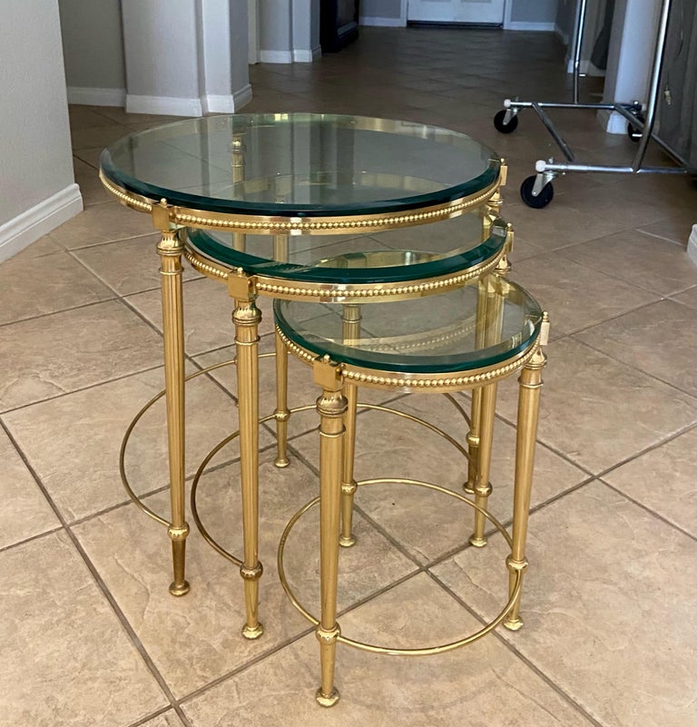 Trio (3) of rounds shaped brass nesting tables with beveled edged glass tops, attributed to Maison Jansen. The solid brass is expertly crafted with refined yet elegant detailing including beaded edging. 
Size each table:
19.5