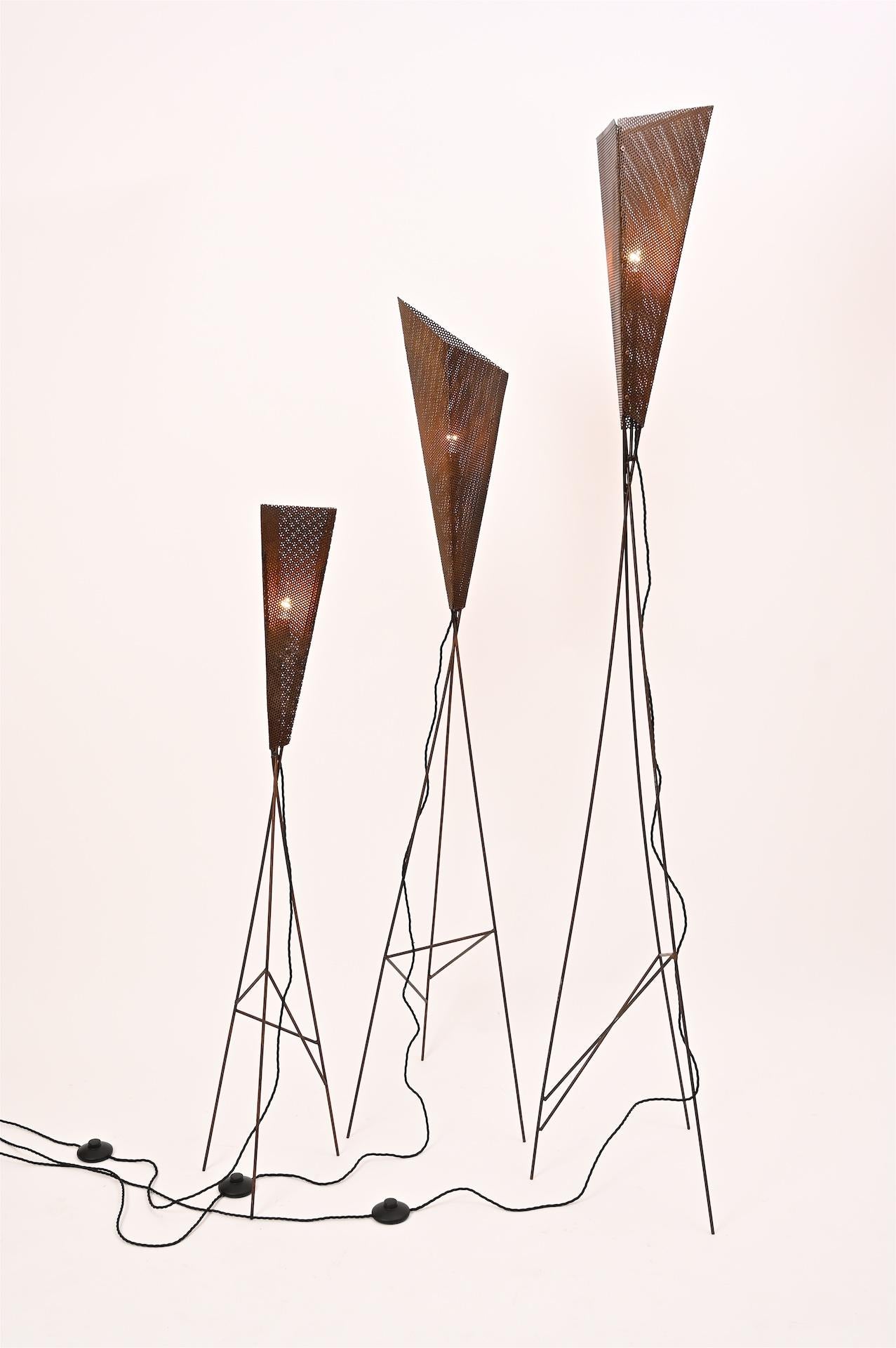 Three tripod floor lamps with perforated metal shades, France, circa 1950.

Sculptural metal lights with great patina

The tallest height 197cm
Shortest 127cm

Re wired fully working each with foot switch

