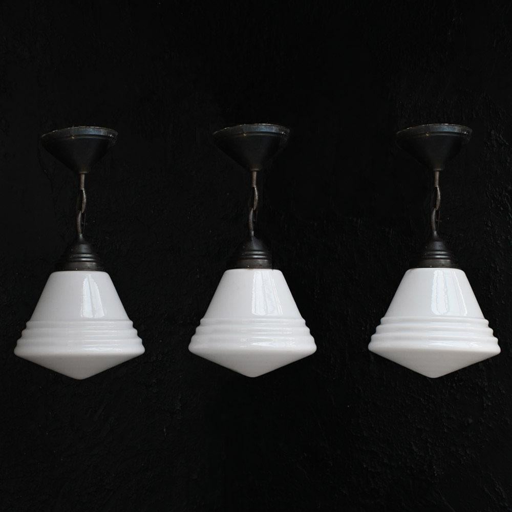 Trio de lampes suspendues Phillips en verre du milieu du 20e siècle 
Ensemble de 3 élégantes lampes suspendues en verre Phillips du milieu du 20e siècle avec des galeries en laiton. Un abat-jour porte encore les restes d'un texte estampillé en gris