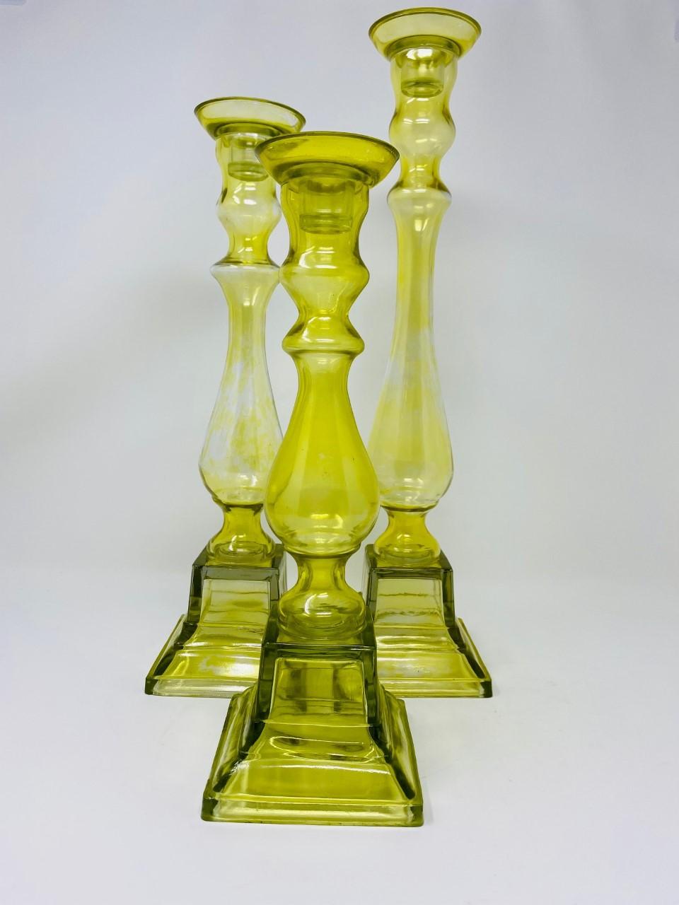 Beautiful set of yellow amber glass candleholders. Each candleholder is a different height and the trio beautifully complement different décor styles with style and beauty. Each piece is designed in a Classic candleholder shape but is constructed in