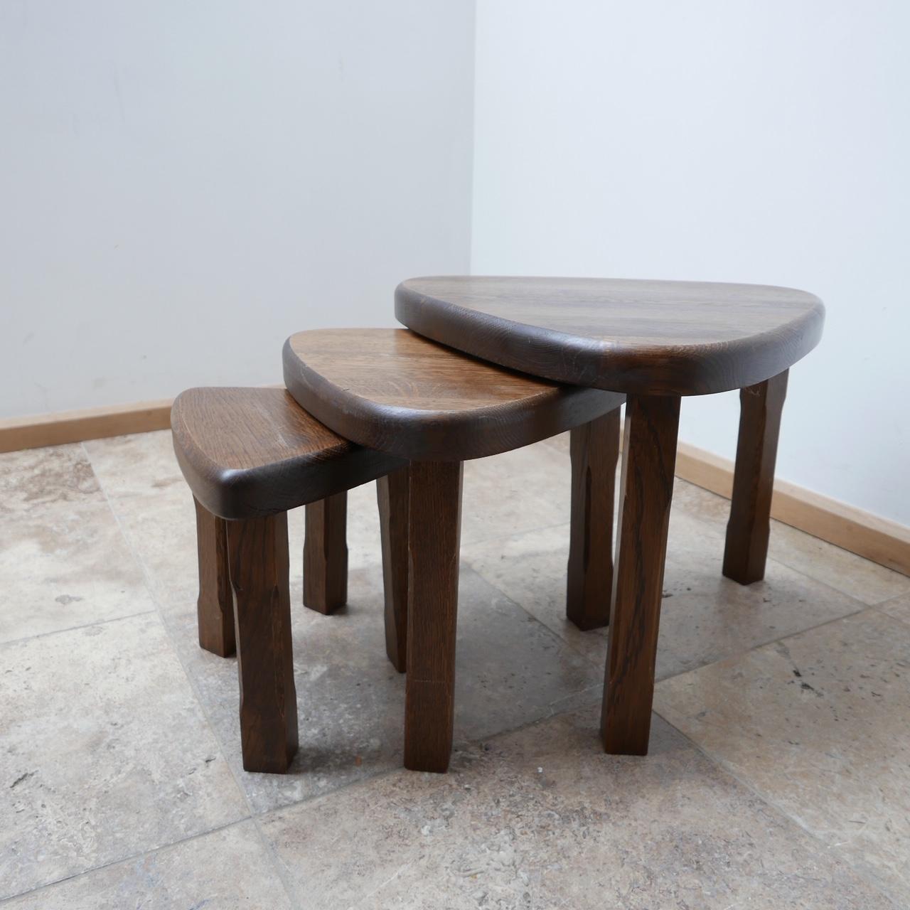 A set of solid stained oak nesting tables. 

Echoes of Chapo's T23 table shape. 

France, c1970s. 

Useful, stylish and functional.   

Can be used in a nest, or set around the room as side tables. 

Dimensions: 48.5 D x 49.5 W x 39 H in