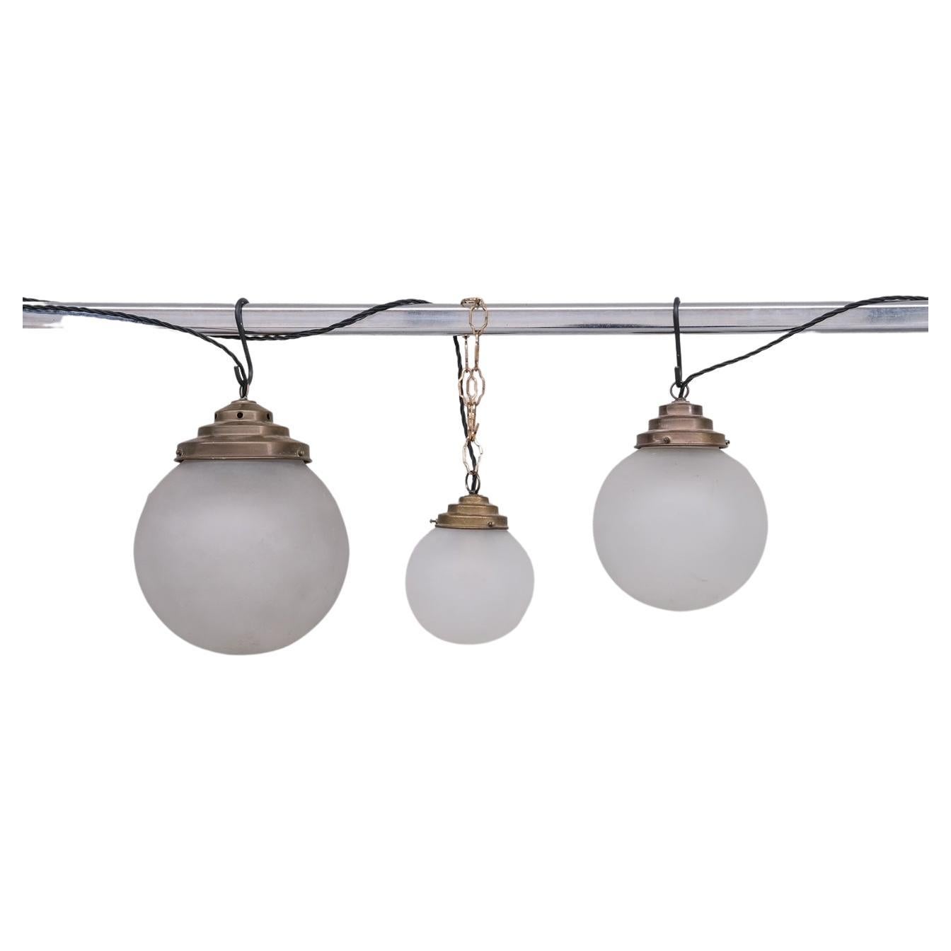 Trio de lampes suspendues en verre opaque et laiton