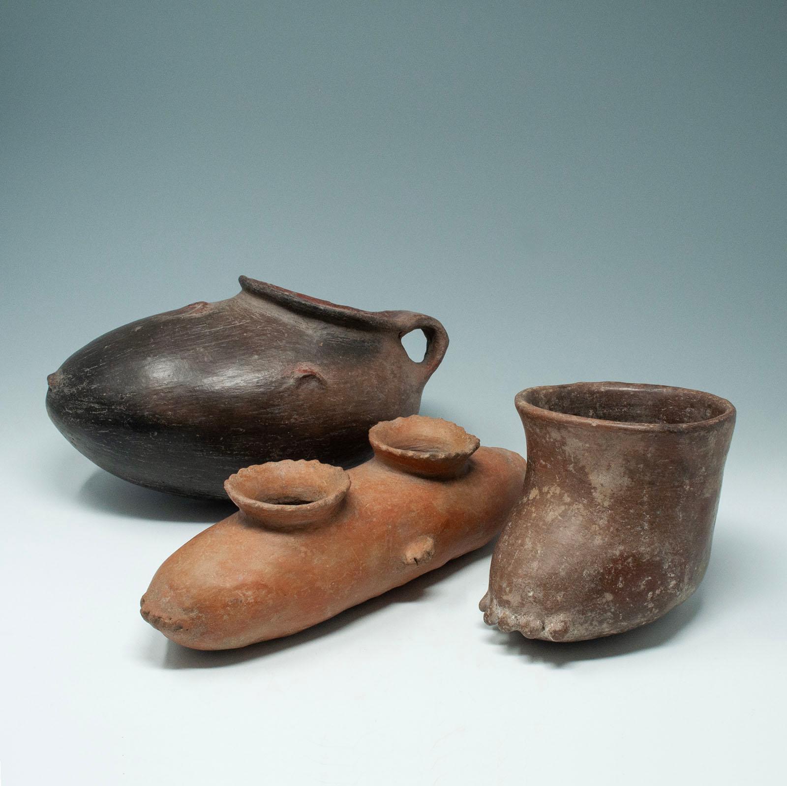 Trio of Pre-Columbian Foot Vessels, West Mexico

The first is a reddish brown pottery shoe vessel from the Chipicuaro culture (ca. 500 BC – 300 AD) with a burnished surface and a wide mouth, which curves into a handle at the back. Two minor rim