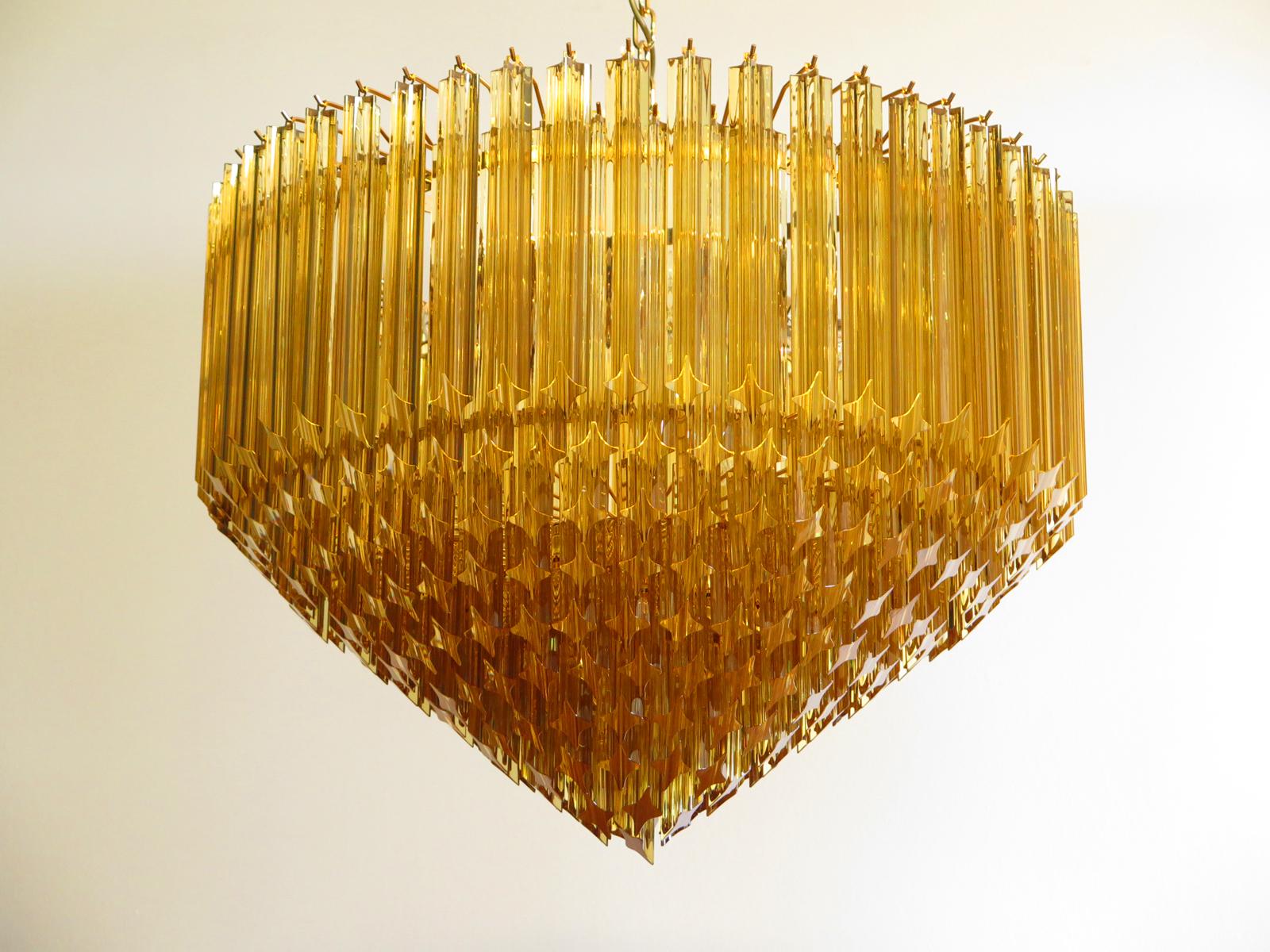 Un magnifico trio di lampadari in vetro di Murano, 265 quadriedri color ambra su montatura dorata. Questo grande lampadario italiano della metà del secolo scorso è davvero un classico senza tempo. 
Dimensioni: 57,10 pollici (145 cm) di altezza con