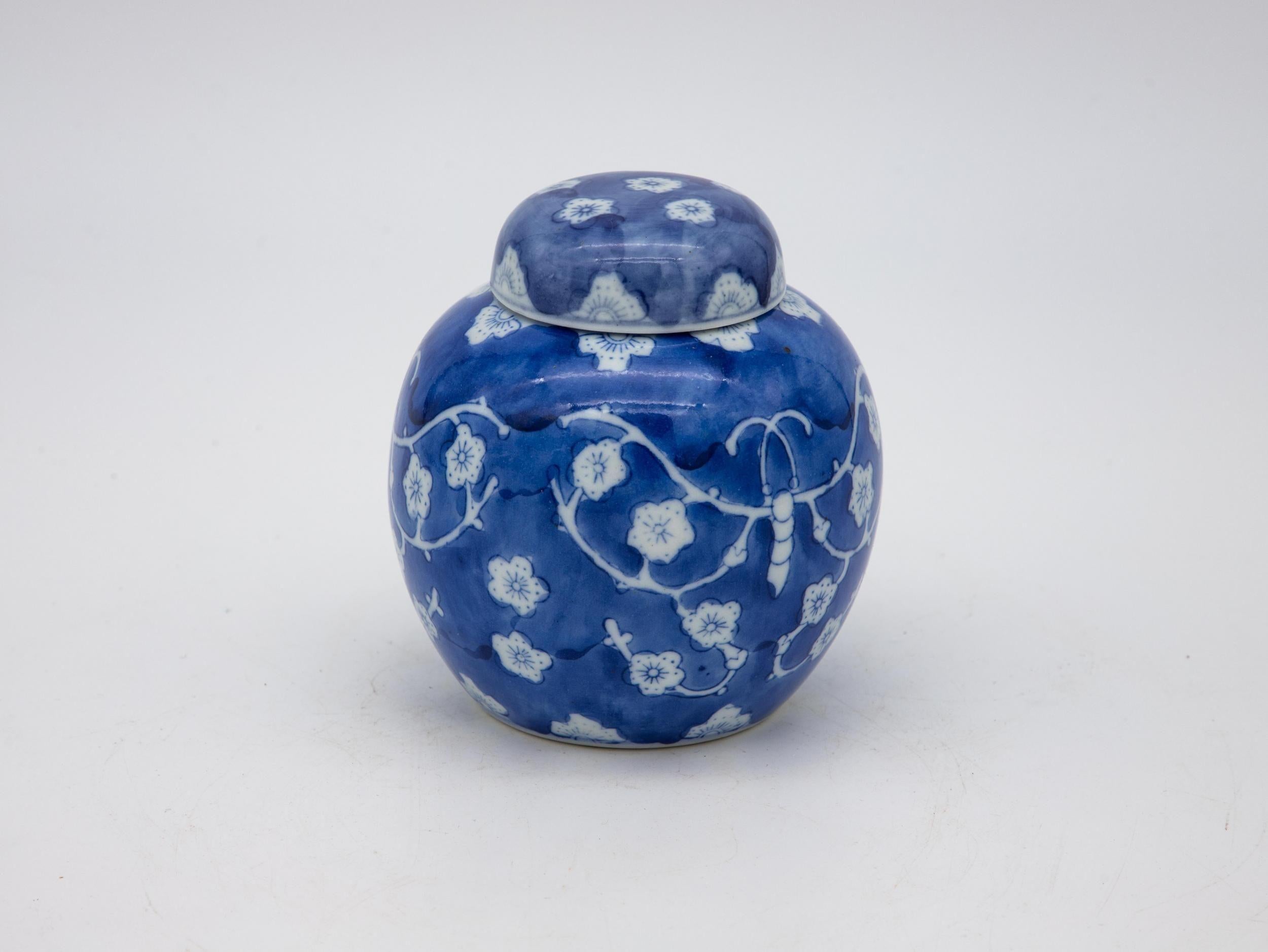 A trio of small blue and white Chinoiserie ginger jars. Two of the jars feature a cherry blossom pattern and one features a lotus blossom. The lids are removable and one has been repaired.