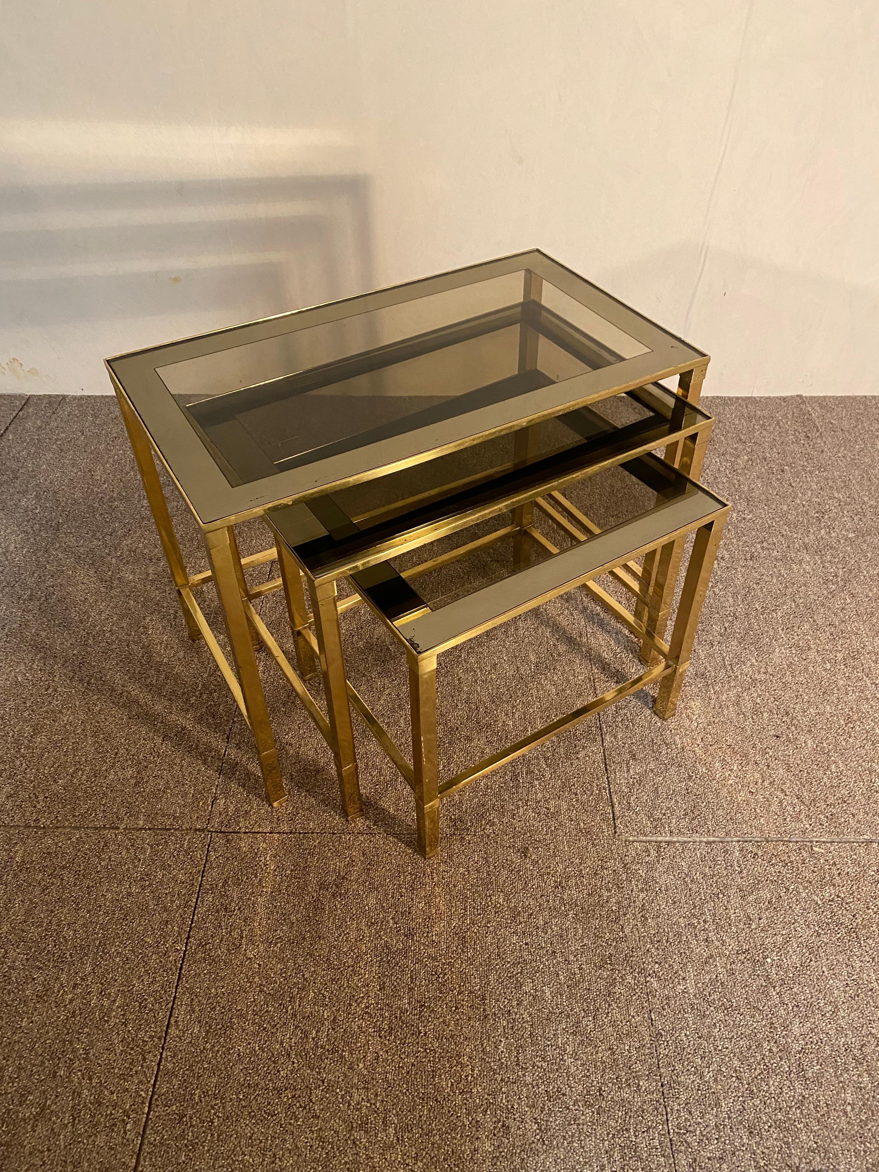Series of three brass nesting tables. Smoked lenses. Italian work from the 70s. In good condition.