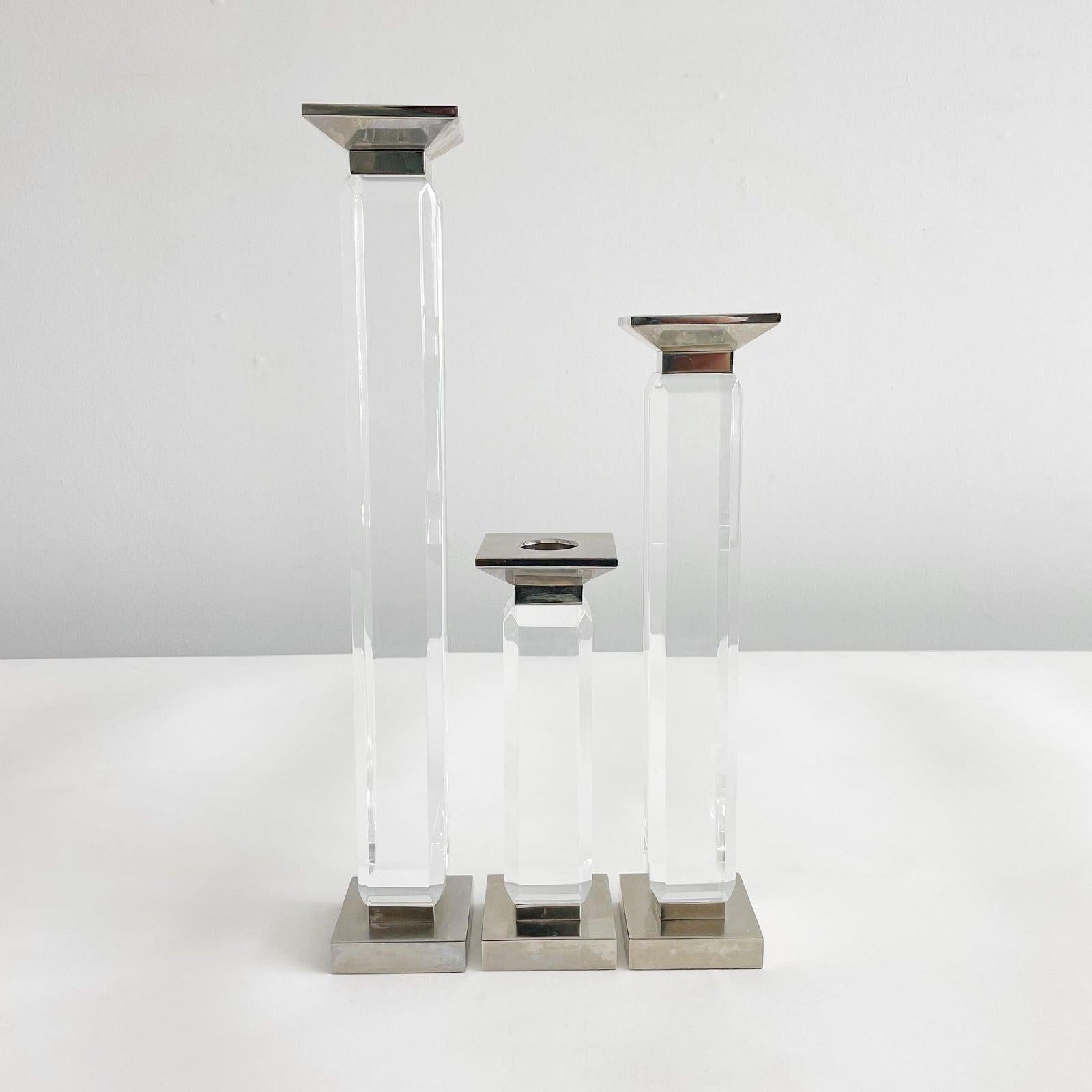 Polished chrome and lucite candle holders in graduating sizes by Charles Hollis Jones. Each base measures 3 inches square. Height of large candlestick is 18.25 inches, medium candlestick is 14.25 inches and small is 9.25 inches.