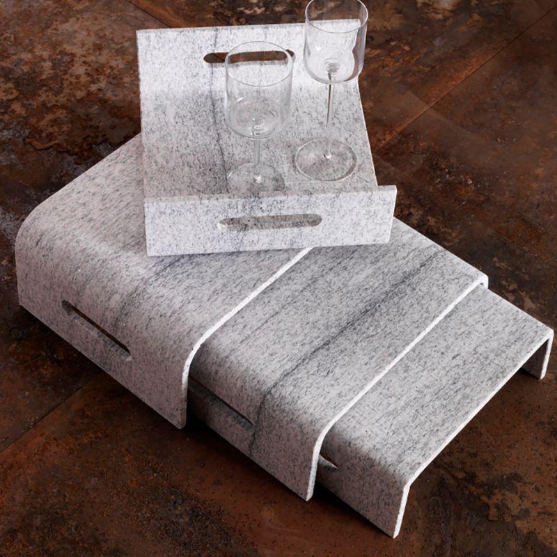 An exquisite set of three small stackable coffee tables or plateaux to enliven a contemporary interior with minimalist yet sublime sophistication, each piece is deftly handmade of Duke White granite following sustainable procedures. An original