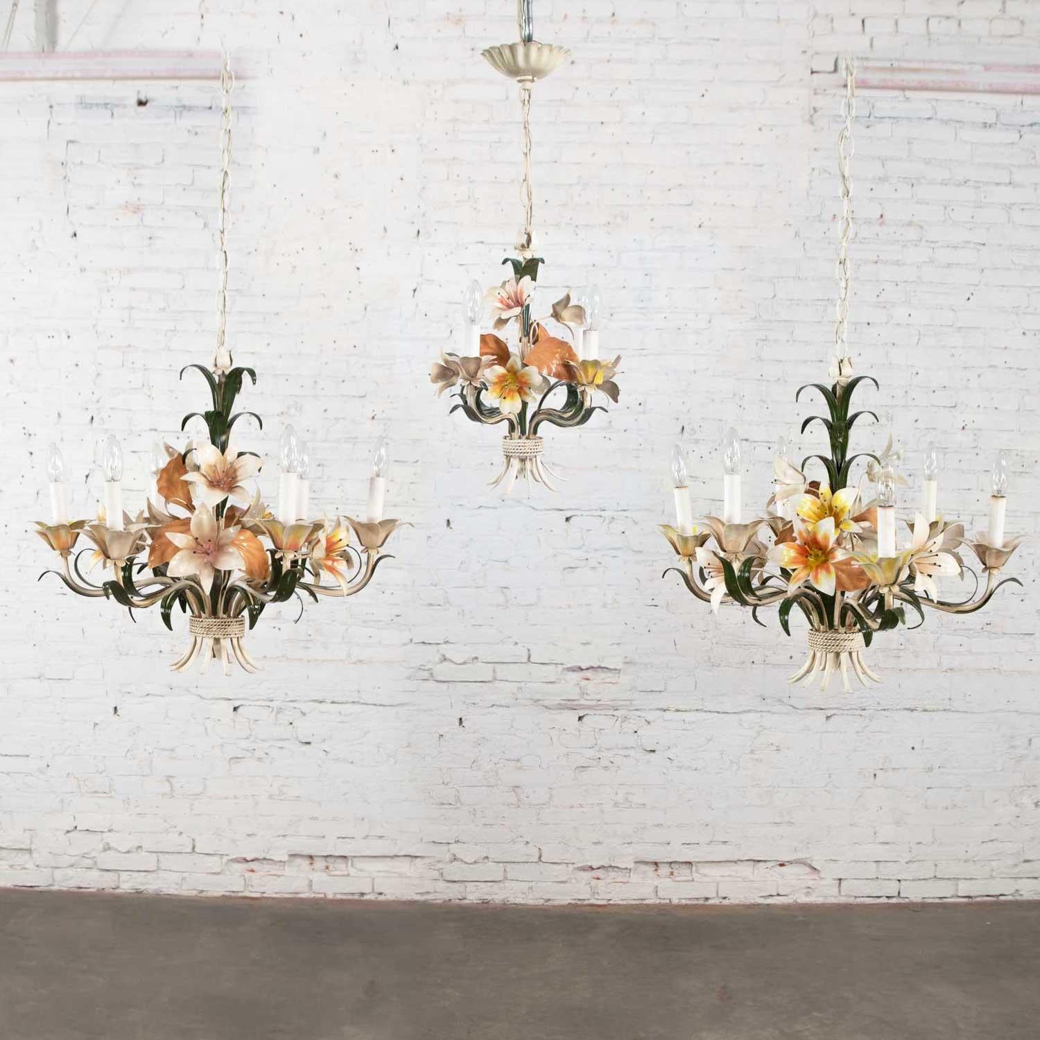 Lovely trio of vintage tole painted floral chandeliers. There are two (2) medium sized chandeliers with 6-light and one (1) small chandelier with 4-light. They are in wonderful vintage condition with no outstanding flaws. We have touched up some
