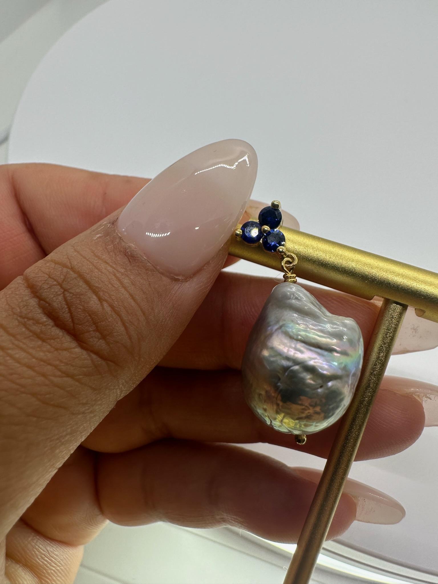  14k yellow gold

 3mm round Ceylon Sapphires

 Deep blue hue

Especially effective for chakra healing— Sapphires are for those who are intent on finding spiritual truth.
 .
Total carat weight: 0.89ct

 Push back 

Freshwater grey baroque pearls