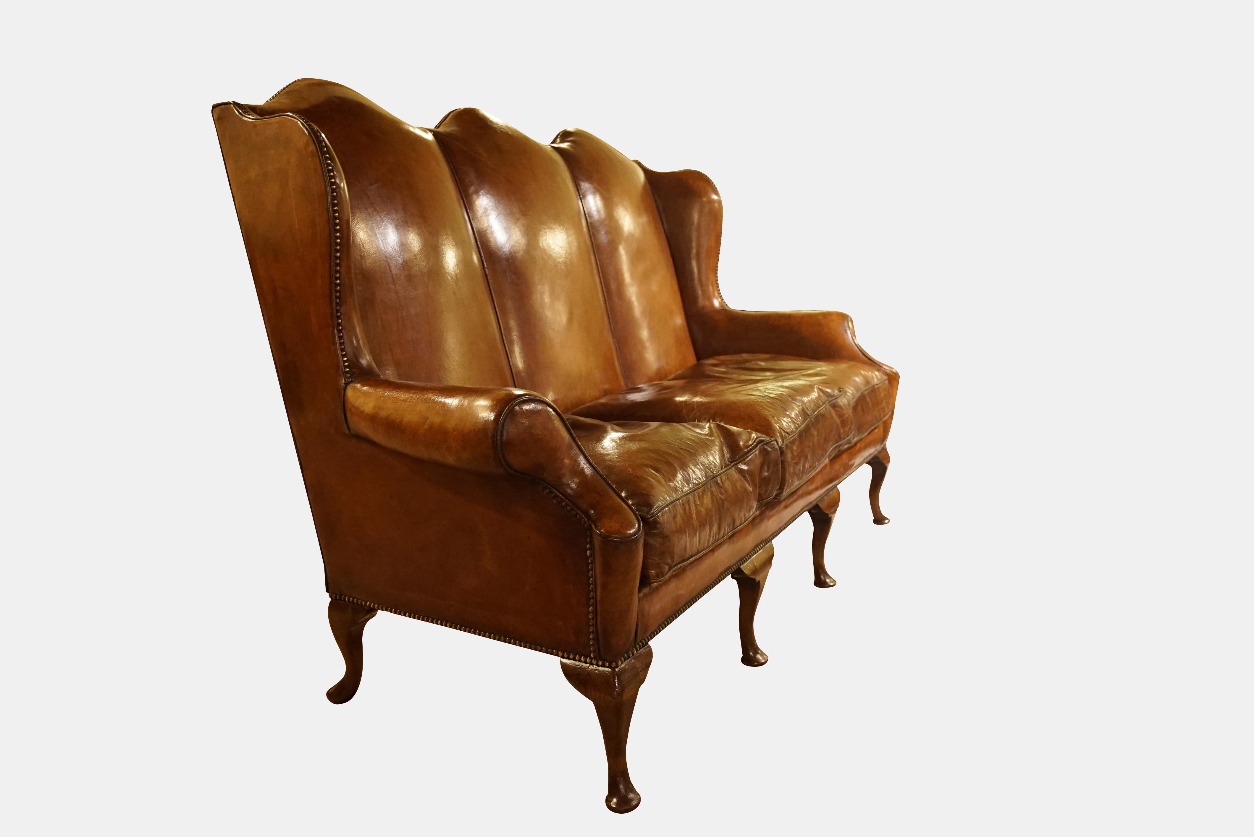 A superb Queen Anne style triple back leather settee, raised on cabriole legs, close nailed wings and scroll arms, all in a warm antique brown hide with feather cushions - exceedingly comfortable,

circa 1910.