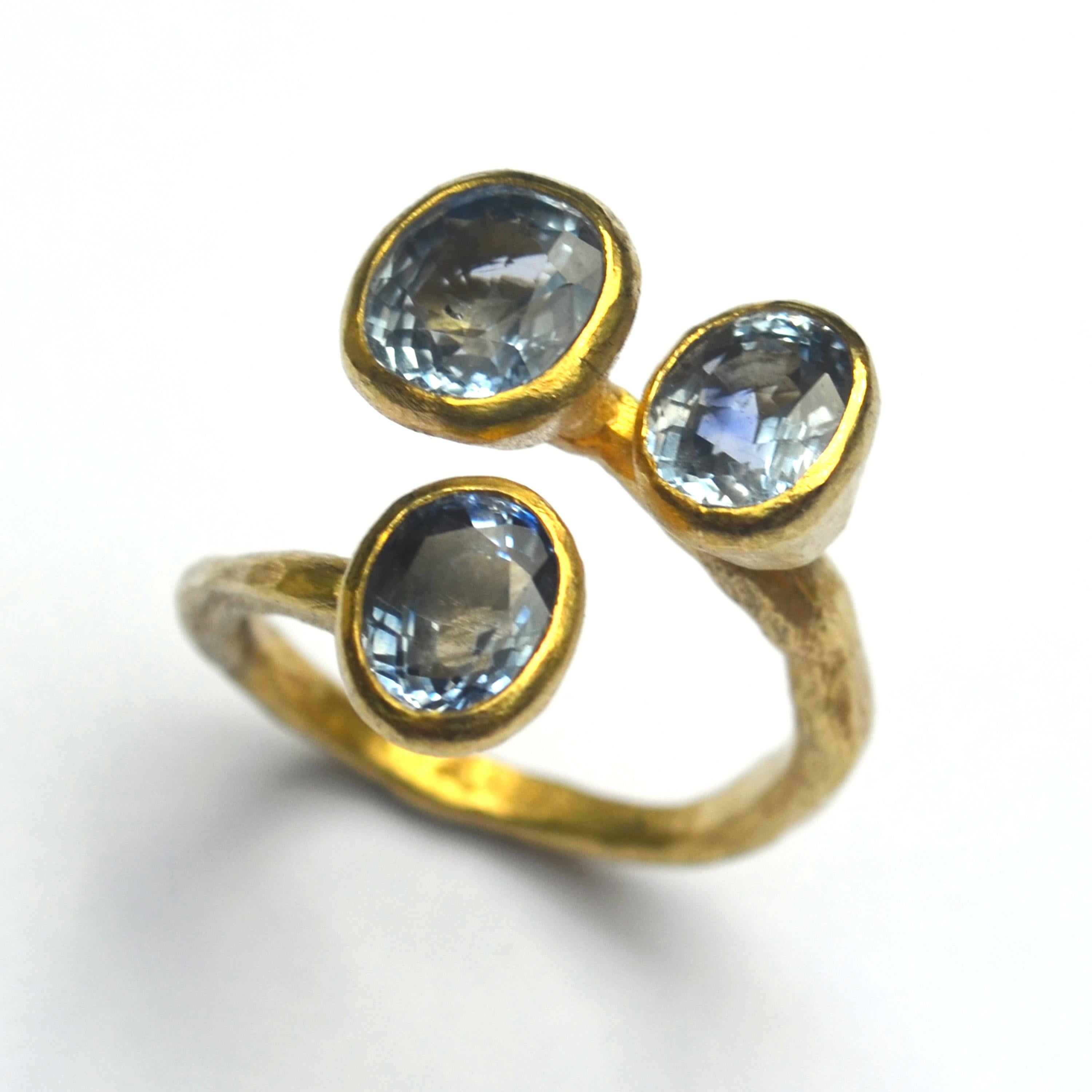Handmade 18k Gold ring by London Goldsmith Disa Allsopp featuring three Lavender Blue Sapphires approximately 5.5 carats in total. The colour is matched in each faceted stone, 2 oval and 1 cushion cut, framed in warm yellow gold on a textured,