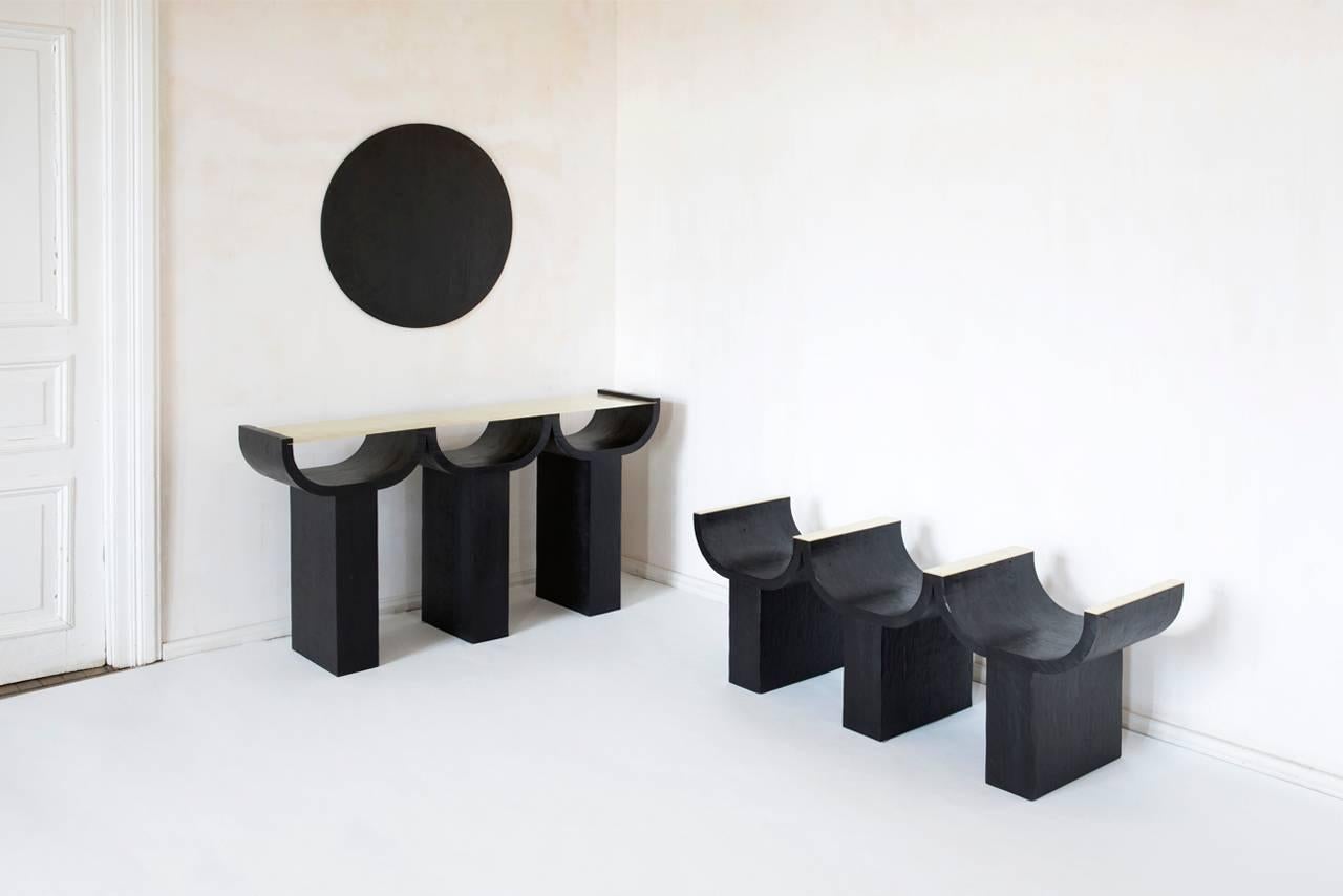 Triple console, rooms.
Dimensions: L 40/ W 165/ H 91.5.
Materials: Brass, aged oak.

Triple Console
Drawing inspiration from ethnic Georgian furniture and the brutalist architectural forms of the Soviet era, darkened wood evokes primitive modes