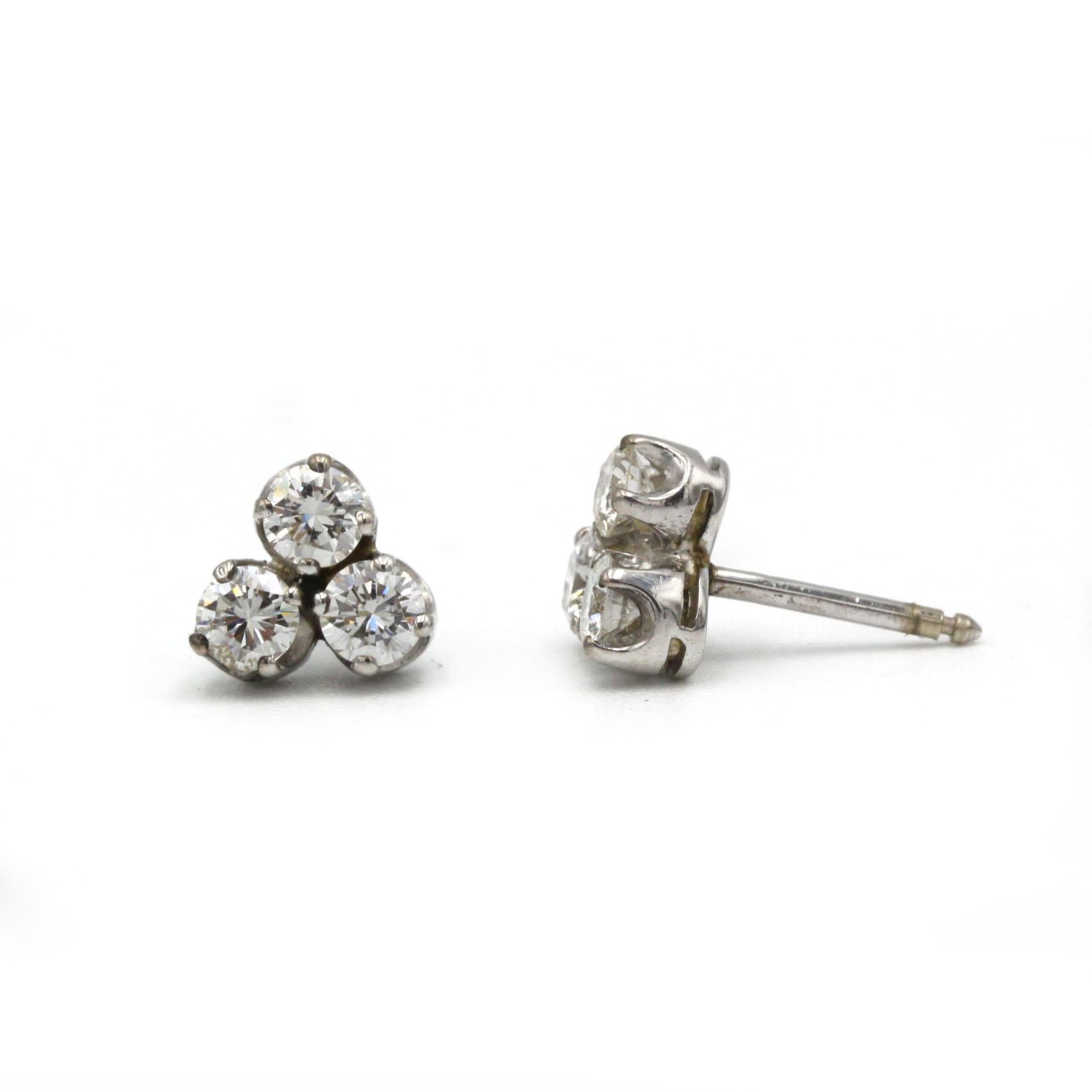 L'élégance discrète rencontre le luxe quotidien dans ces boucles d'oreilles en or blanc 18 carats, chacune présentant un trio de diamants taille brillant regroupés avec art dans un arrangement triangulaire. Les pierres serties captent la lumière