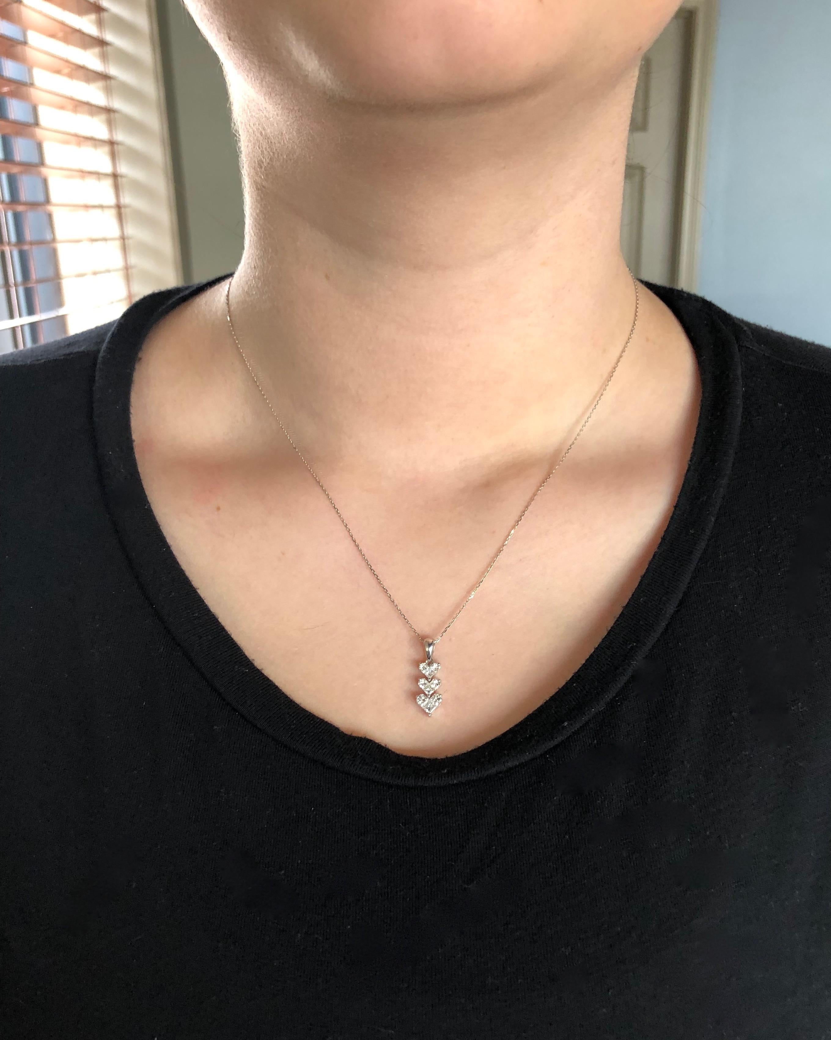 This unique necklace features three stunning invisible set heart shaped diamonds set in an elegant drop. 

Diamond Carat Weight: .83CTW
Diamond Cut: 3 Princess Cut, 6 Fancy Cut Half Round
Color: Average G-I
Clarity: Average VS
Metal: 18K White