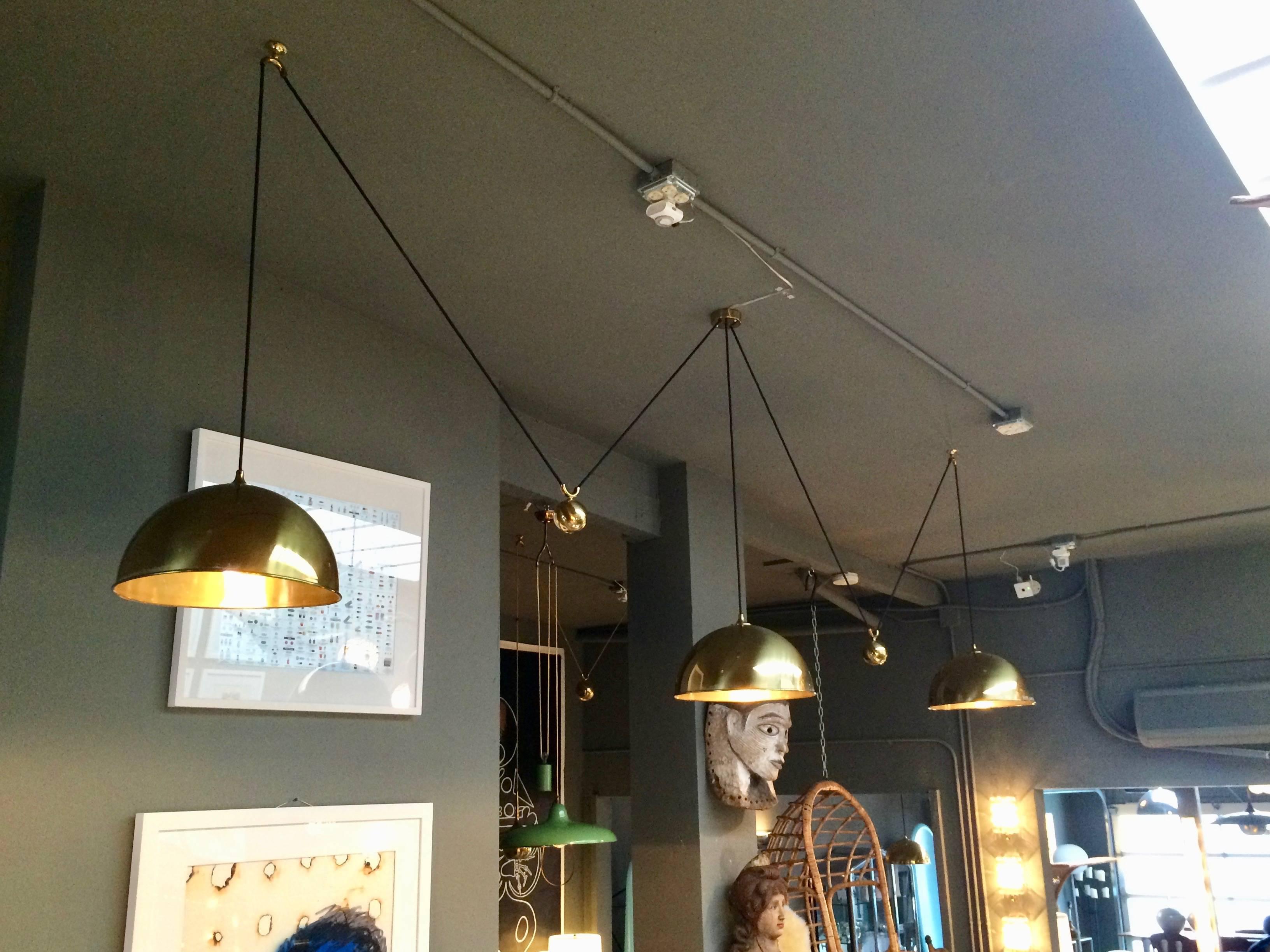 Extremely rare triple counter balance pendants by Florian Schulz. Three brass domes with brass counter weights, canopy and hardware. Black cloth cord. Center brass pendant is manually adjusted to the desired height and held by a set screw inside the