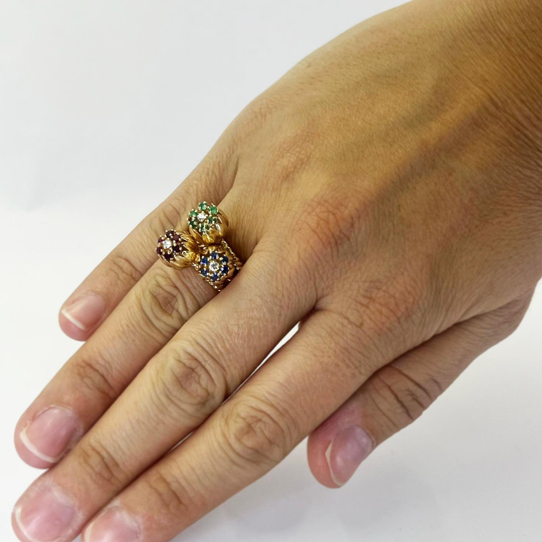 14 karat yellow gold tulip flower stack ring featuring 6 round rubies, 6 sapphires, and 6 emeralds accented by 3 round diamonds. Finger size 5.5 with triple rope design. Includes one sizing service prior to shipping, upon request. Finished weight is