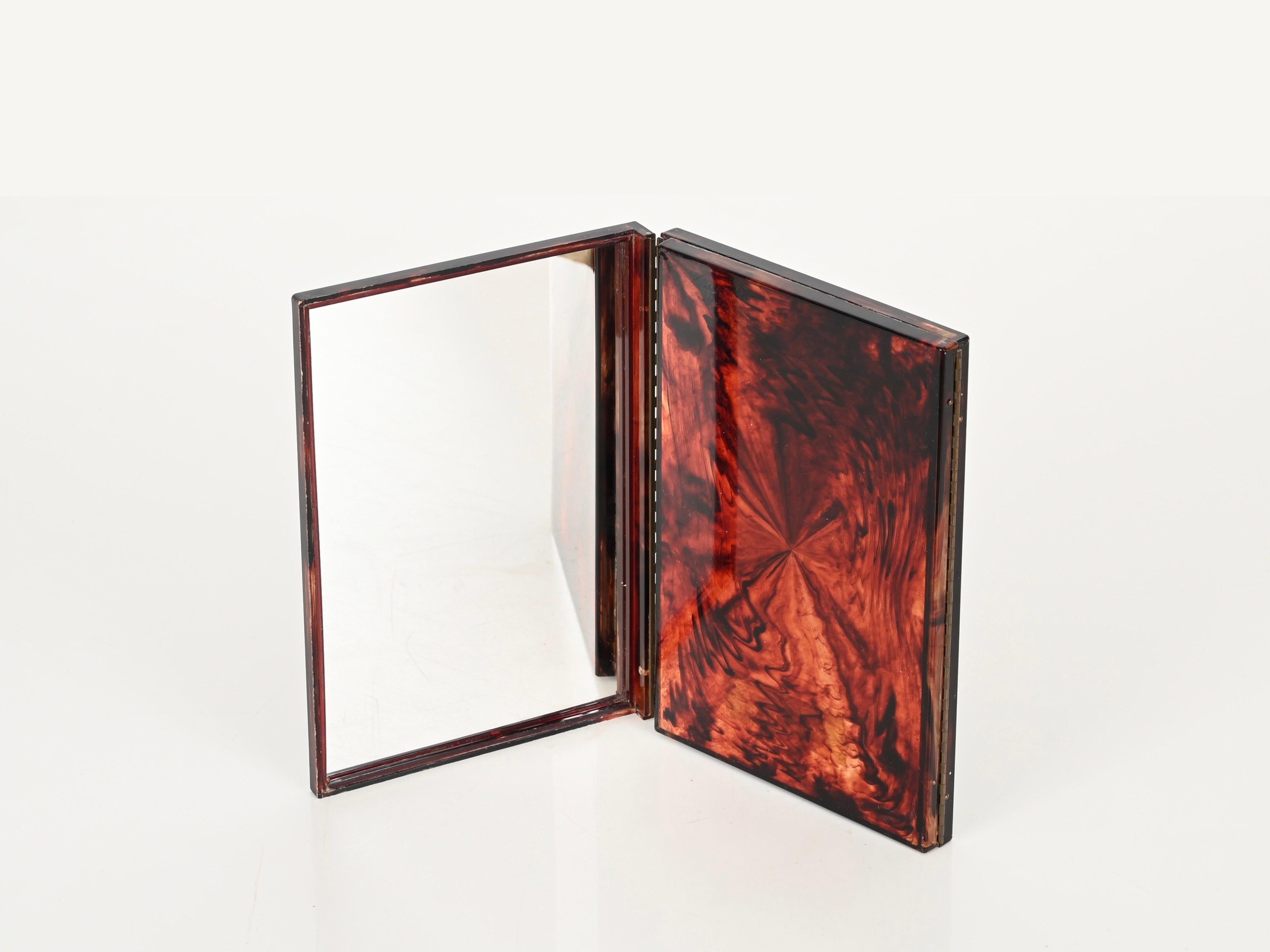 Wonderful Italian vanity folding table mirror in tortoiseshell effect lucite and brass. This unique piece was designed in the 1970s in Italy and is attributed to a Dior Home production.

The tortoiseshell effect lucite, together with the brass