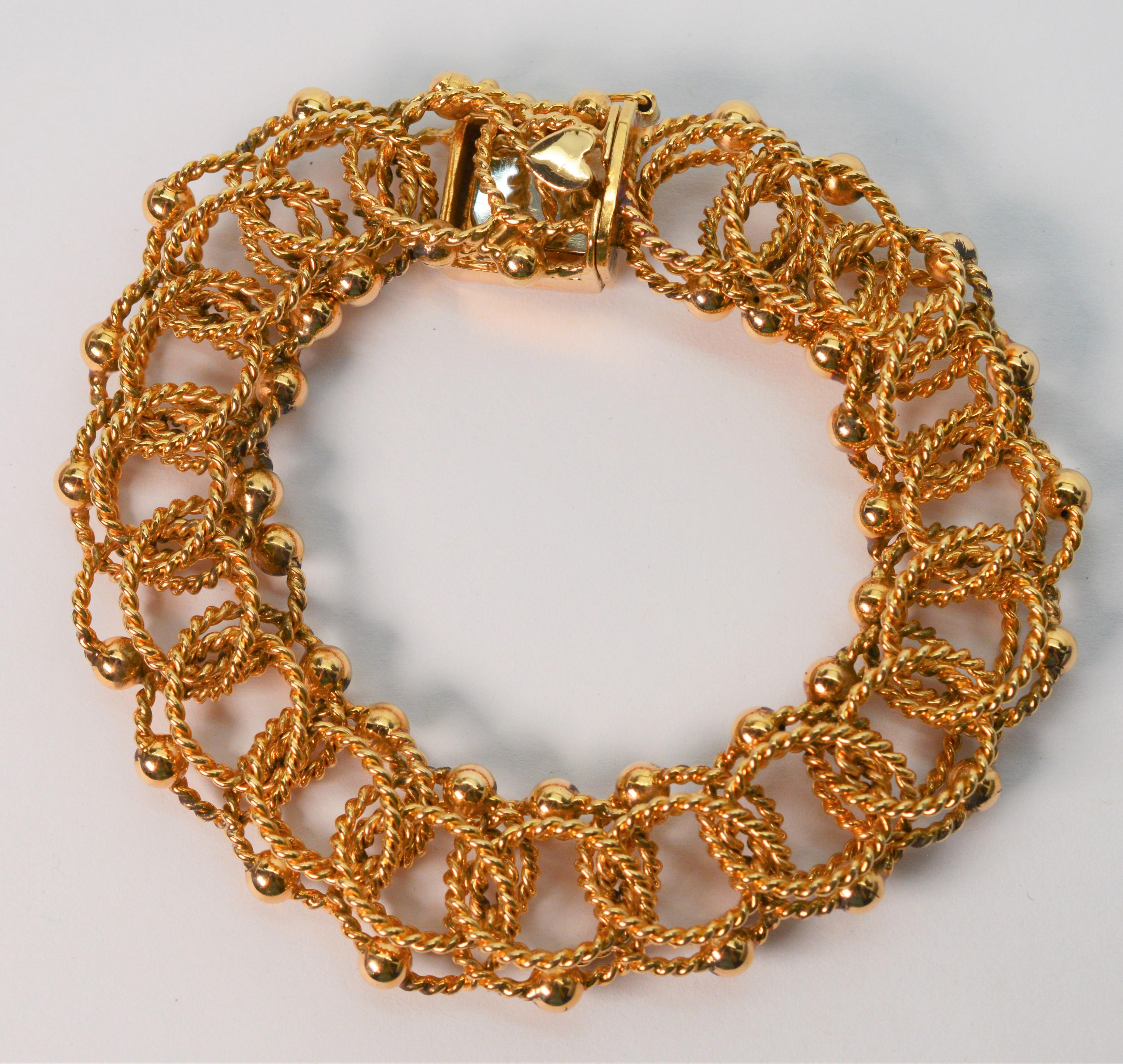 Three twist of bright fourteen karat 14K yellow gold rope create each nested link on this fine retro charm bracelet. Each link intertwines, woven with the next and creates the 7.5 inch length.
Decorative gold ball accents adorn the edges and create