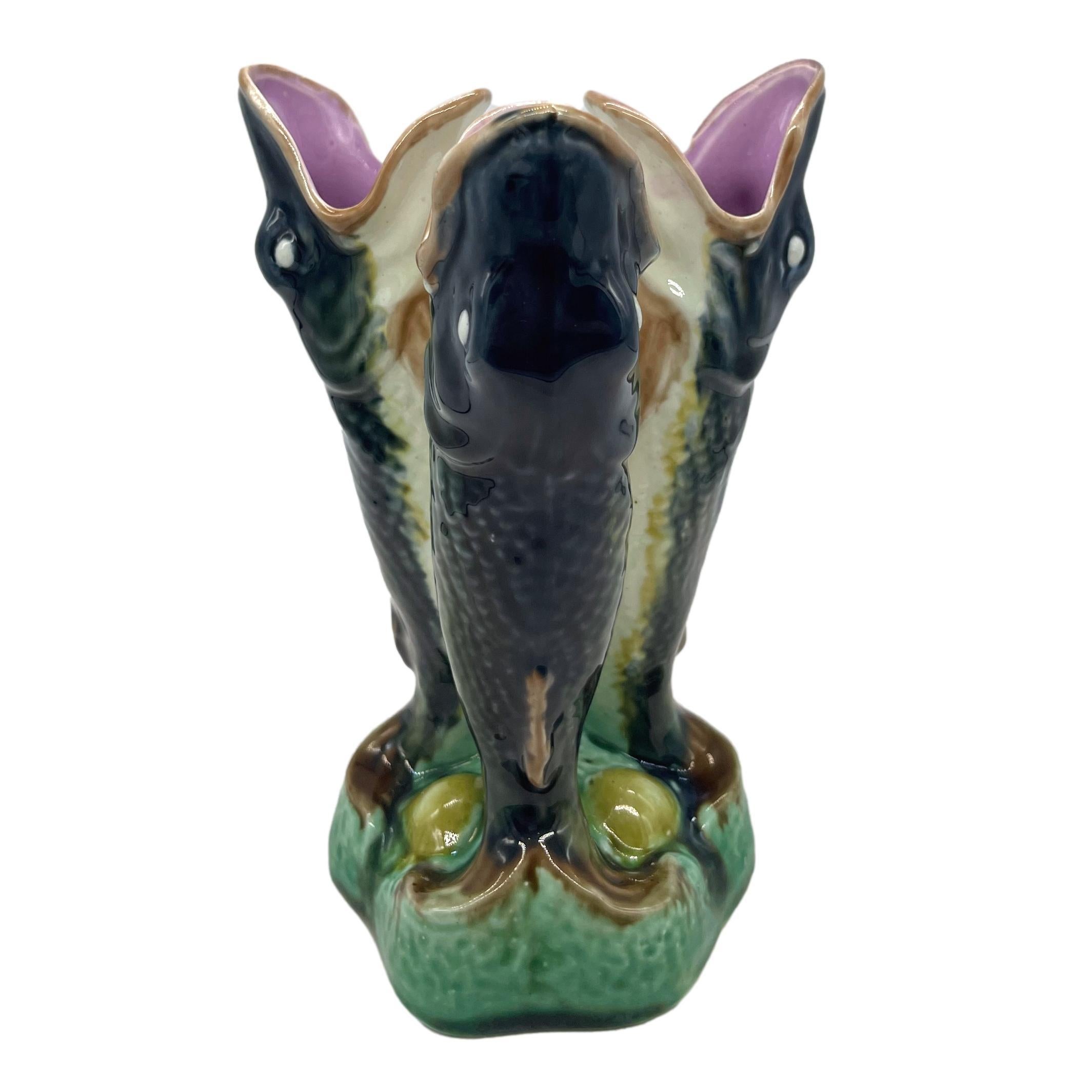 Adams & Bromely Majolica triple posy vase, molded as three interlocked gurgling fish naturalistically glazed with pink interiors, on a mound-form base of shells and seaweed, the yellow glazed reverse with impressed design number, '44' and partially