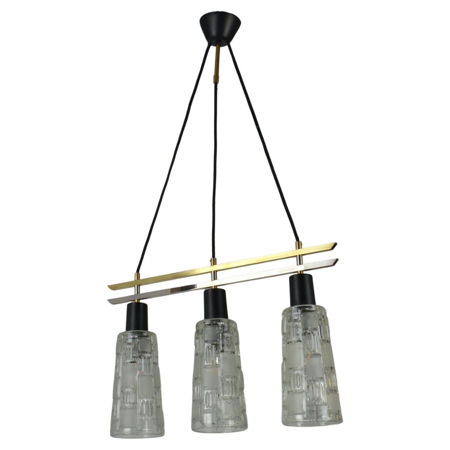 Triple light glass 1960s chandelier has a frame of brass, chrome and black metal that brings the shades together. The relief shades are partly etched mat to diffuse the light. 
The lamp will look great over a dining table.

Dimensions shades;