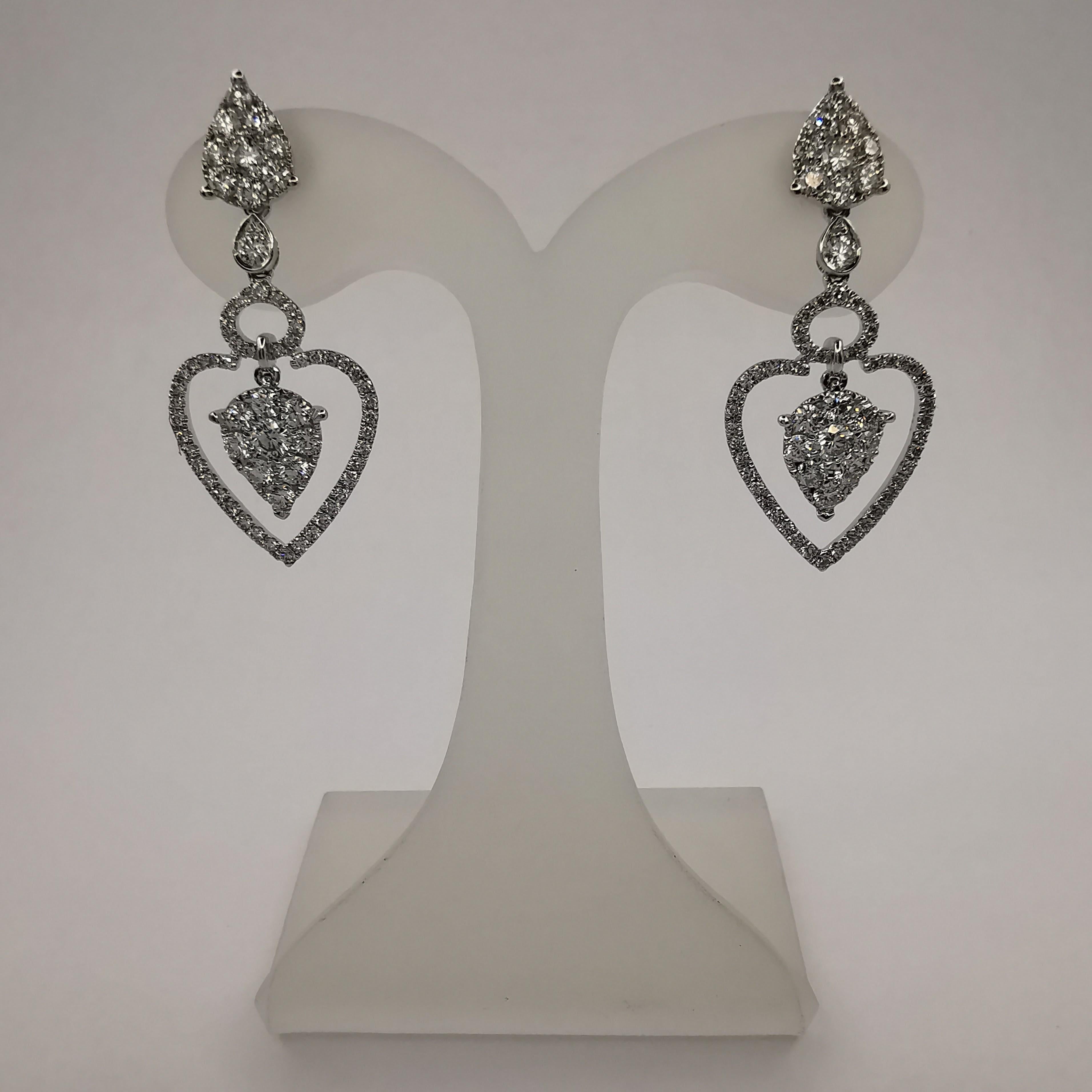 These stunning triple teardrop diamond dangling earrings are a true masterpiece of fine jewelry. Crafted in 18K white gold, each earring features a dangling inverted pear/teardrop-shaped diamond cluster within a halo, held by an upper dangle and a
