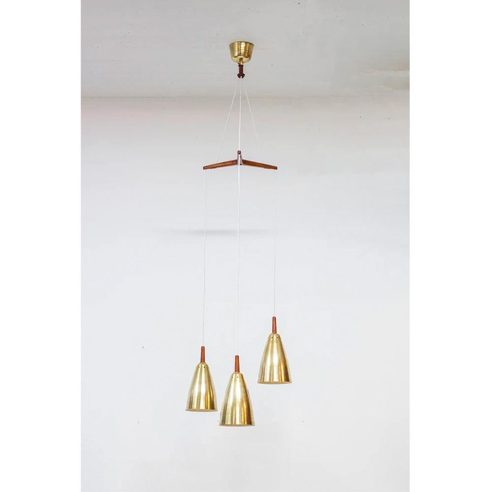 Magnificent adjustable pendant light with its triple lampshades in solid brass and teak, designed by Hans Agne Jakobsson. The solid teak triangle has the designer's signature. Furthermore, the ingenious and original assembly of materials gives this
