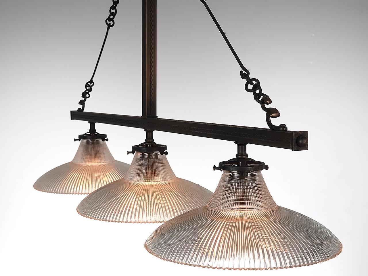 This is a nice light and airy triple chandelier. Its all brass with 3 prismatic prismatic dish shades. The detail is subtle featuring engraved or stamped decoration on the square tubing. It takes 3 standard bulbs and is perfect for a dinning room or