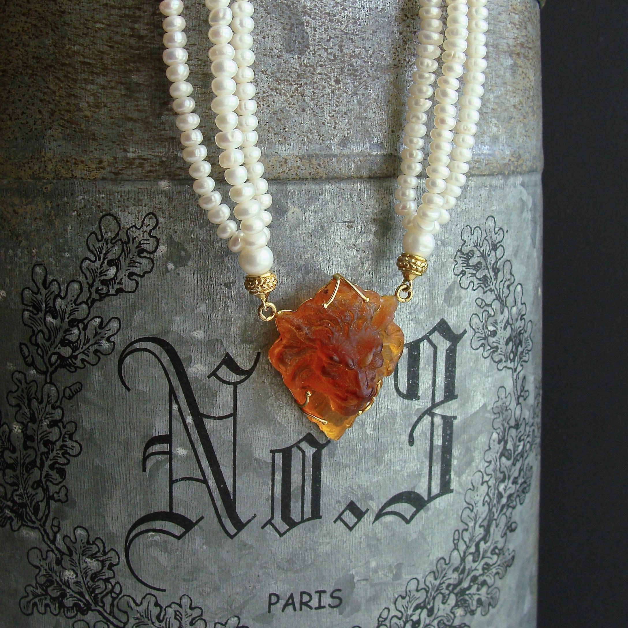 A remarkable Venetian glass intaglio featuring a three dimensional lion in a whiskey quartz coloring, has been married to a triple strand of creamy white small button pearls.  This rich and elegant combination is highlighted with a gold vermeil
