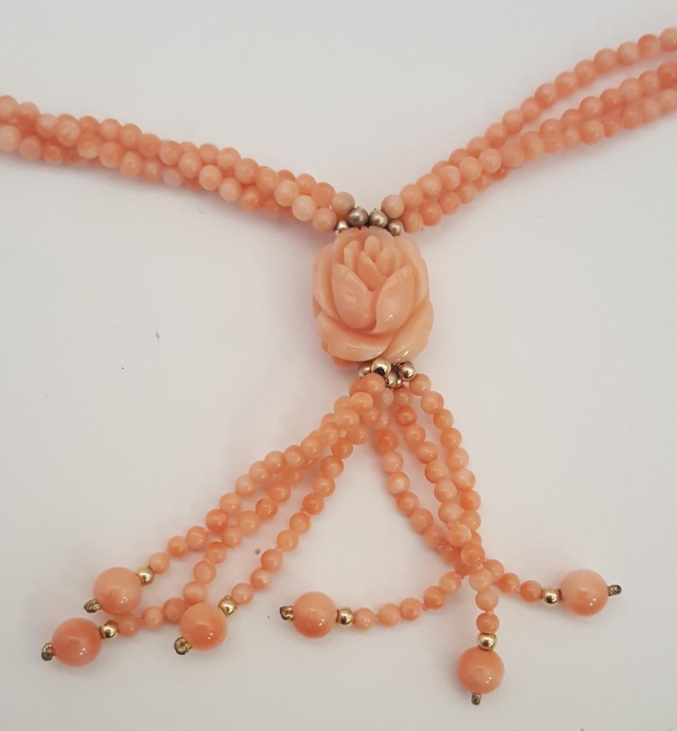 Feminine and fabulous!  A triple strand of 3mm coral beads meet together to present a magnificent carved flower, measuring 14.5mm, followed by a six strand tassel of 3mm coral beads finished with 6mm coral beads.  14 karat yellow gold filigree pearl
