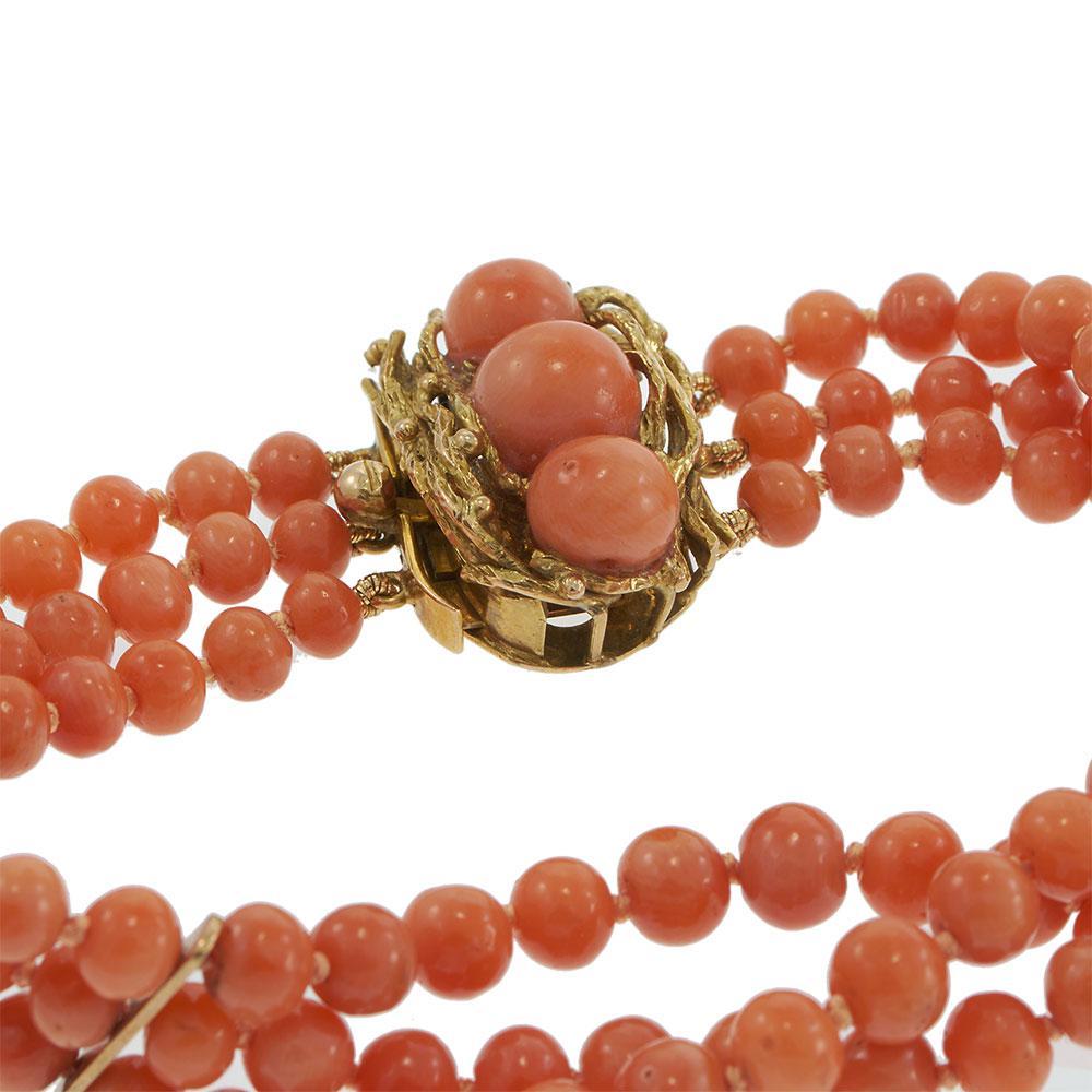 Témoignant d'une chaleur naturelle et d'un grand talent artistique, ce bracelet estate présente trois rangs de perles de corail riche et naturel fixés par un fermoir artisanal en or jaune 14KT serti de cabochons de corail assortis. L'orfèvrerie