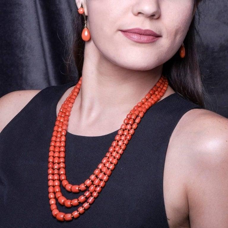 This elegant Vintage necklace incorporates three strands of graduated barrel-shaped Natural Salmon Red Coral beads measuring from 11mm to mm in diameter. The coral beads are silk-strung and inserted throughout the three strands by enchanting 18K